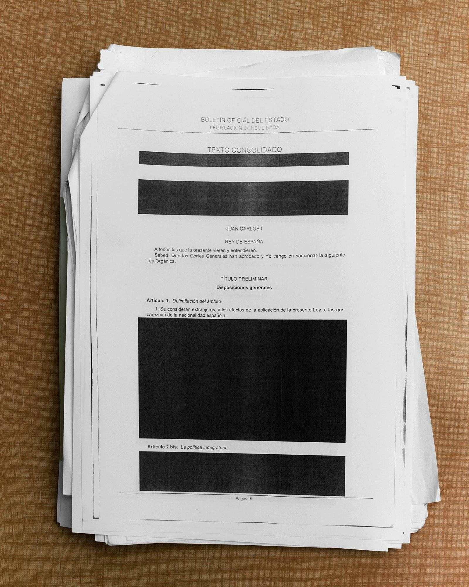 Image of a stack of paper printed with the Spanish immigration law, including blacked-out parts. © Felipe Romero Beltrán