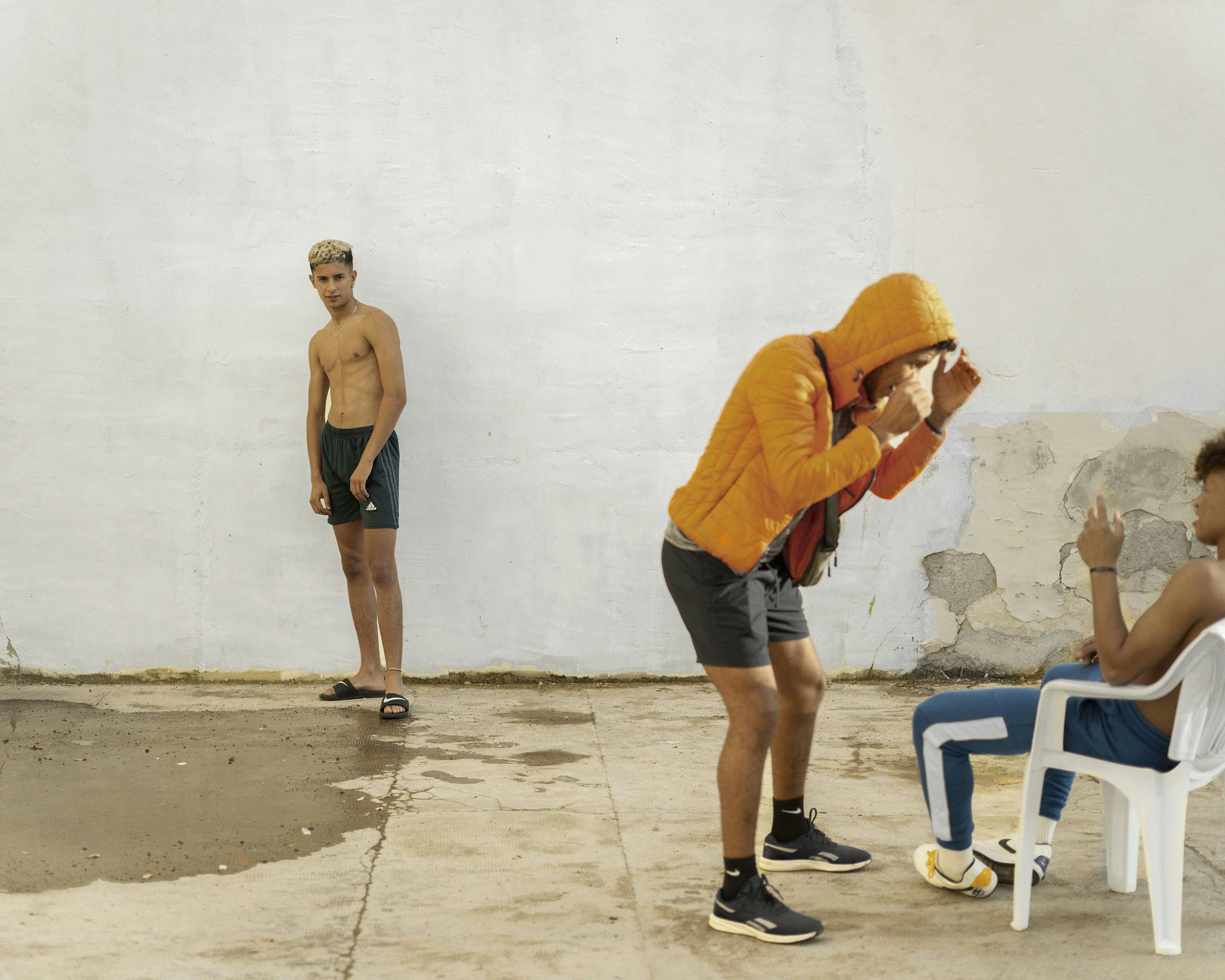Image of three young men in a courtyard, interacting with each other. © Felipe Romero Beltrán