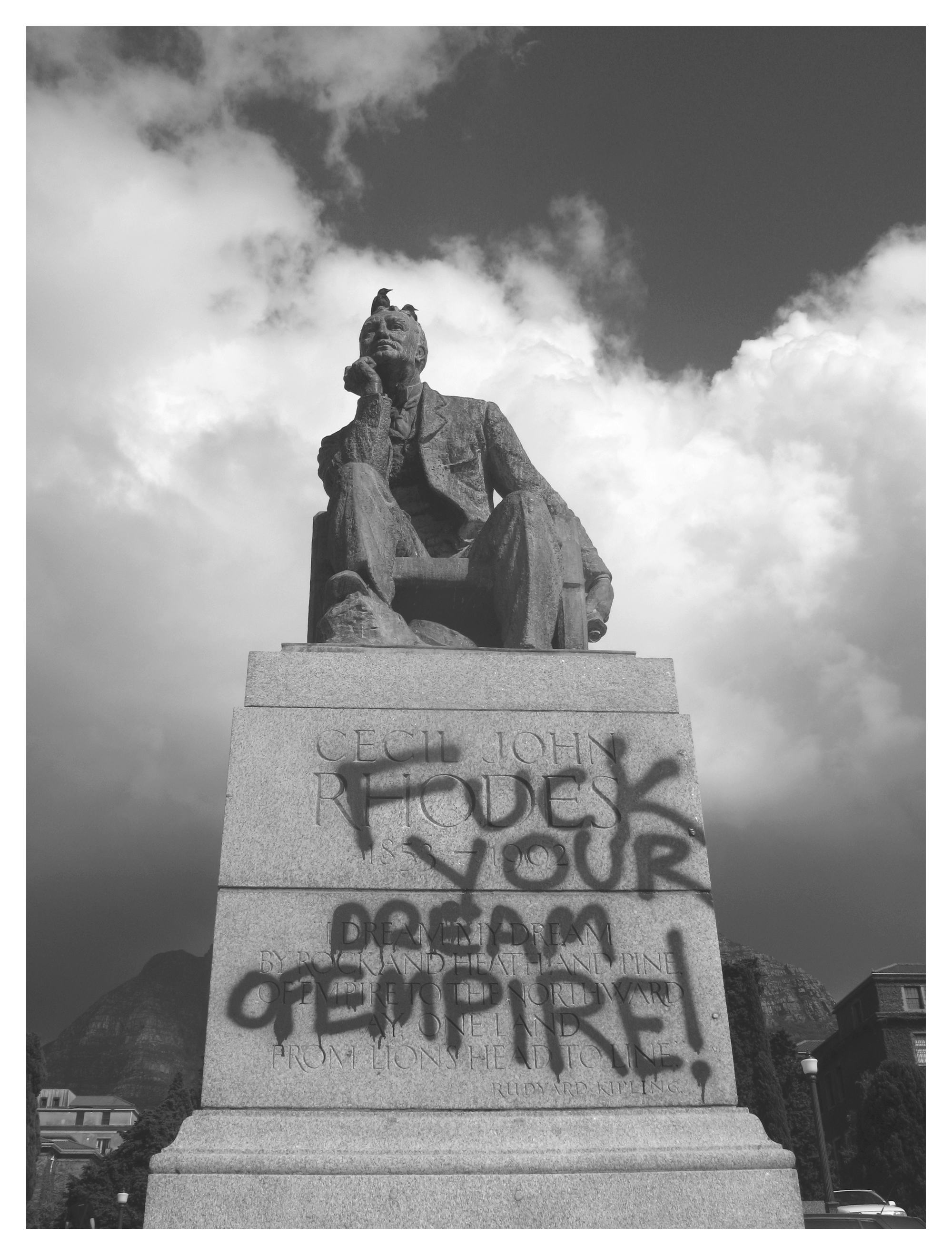 Black and white photo of the Rhodes statue in Cape Town with 'Fuck your Dream of Empire' written on it with grafitti