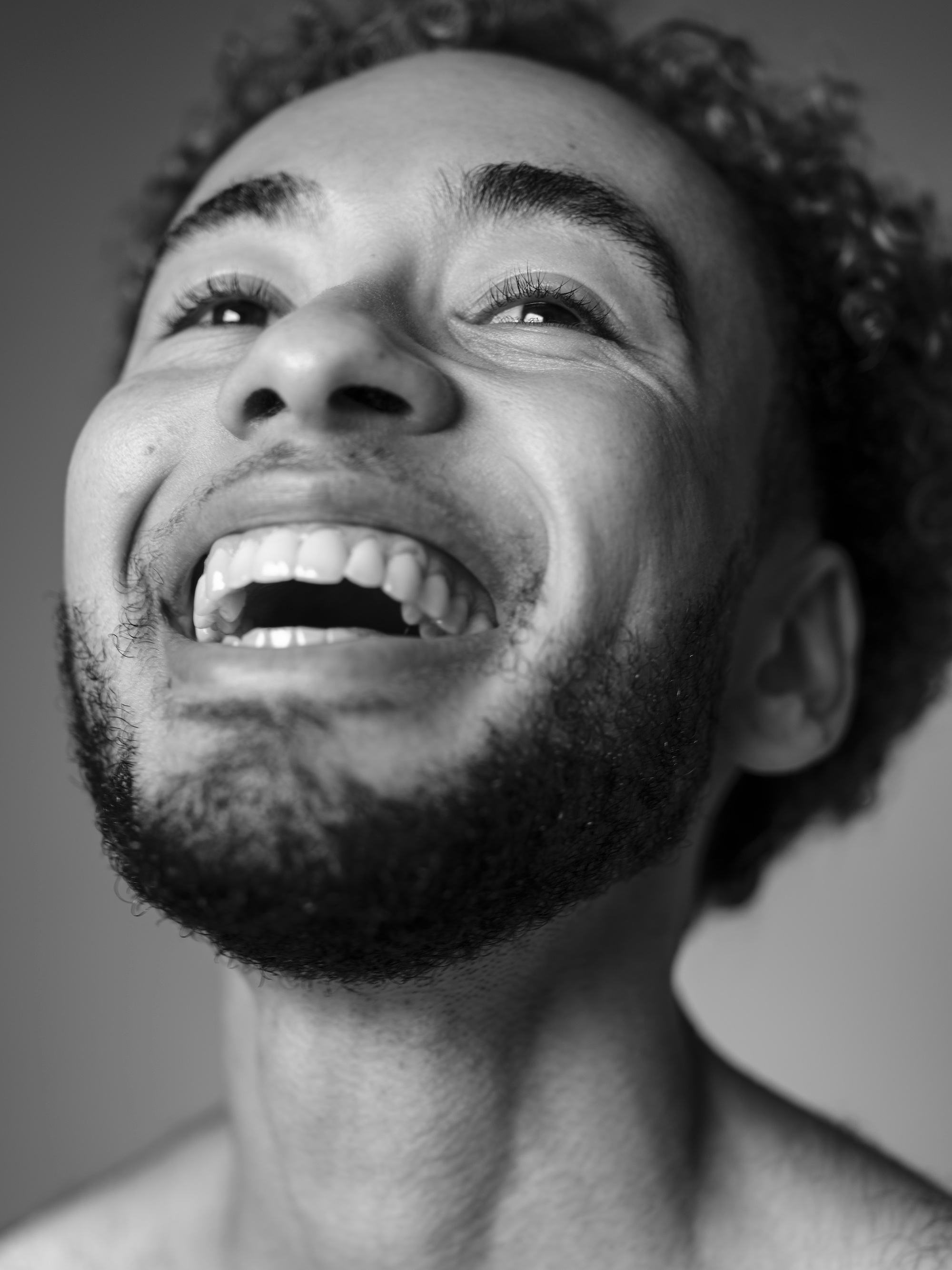 A black-and-white close-up portrait of the photographer, Marvel Harris, looking up and smiling brightly