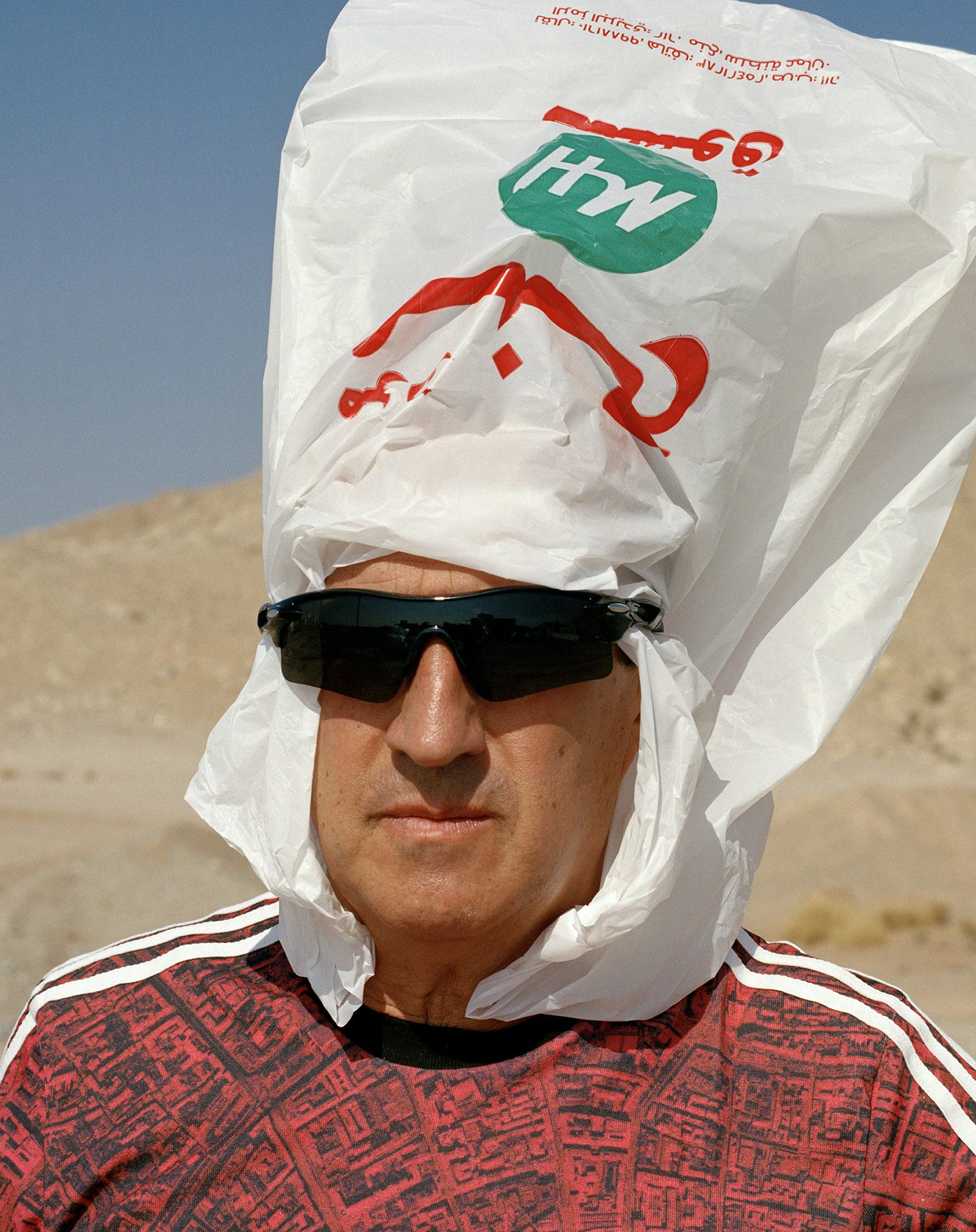 man with plastic bag on head red tshirt and black sunglasses