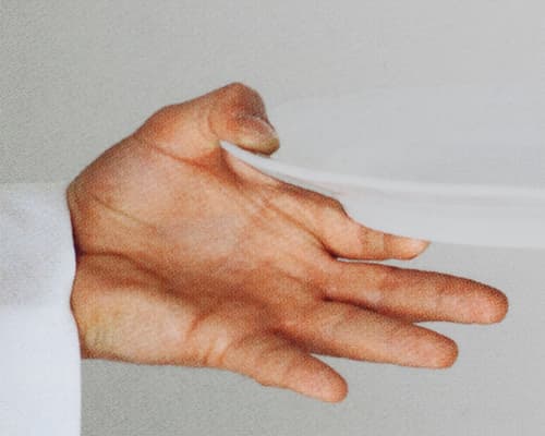 Close-up of an archival image showing a waiter's hand holding a plate. © Eleonora Agostini