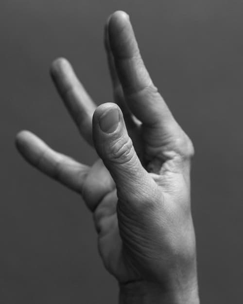 Close-up of a hand, in a forced gesture, appearing to hold a serving plate. © Eleonora Agostini