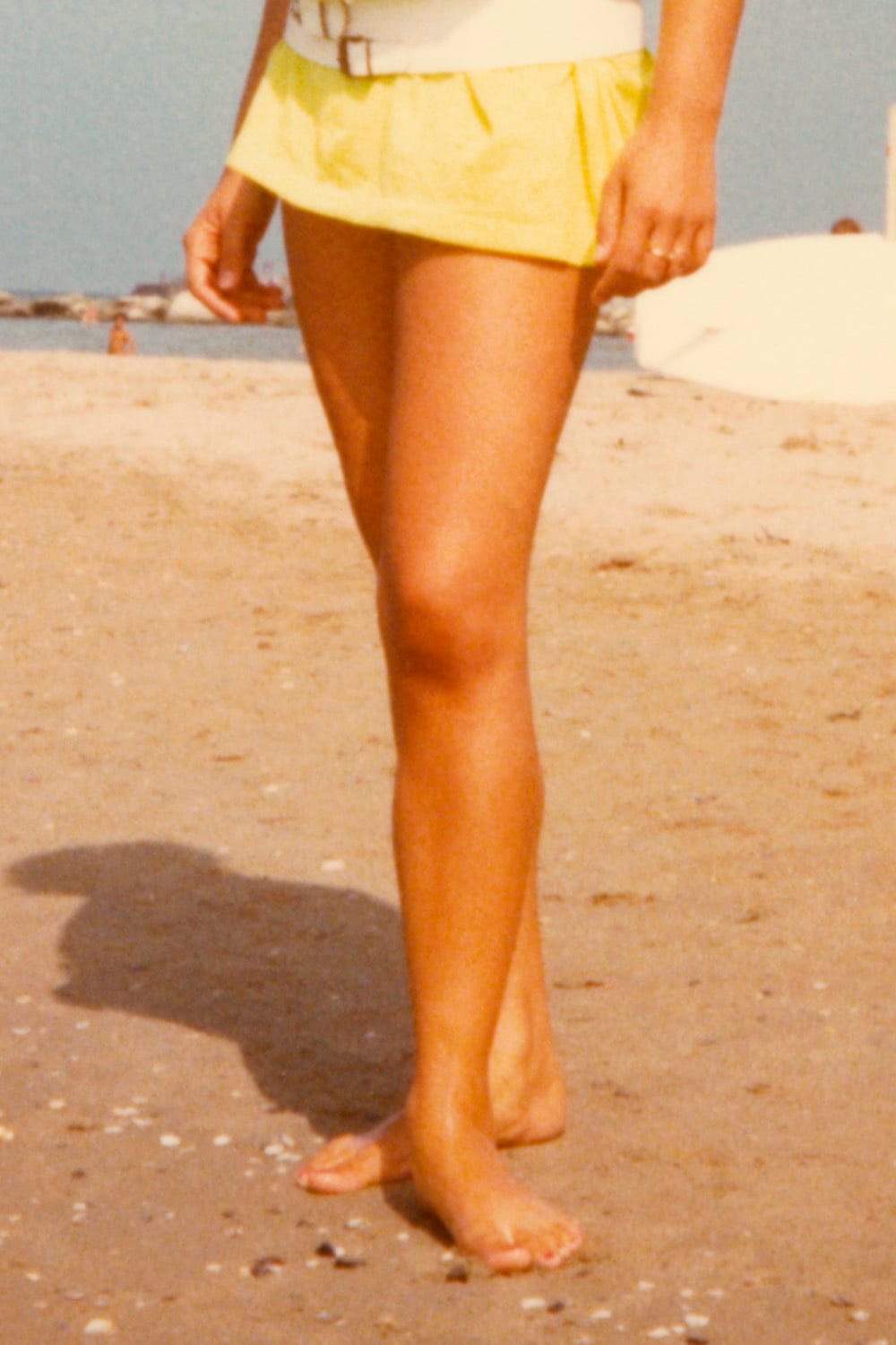 Archival image showing the bare legs of a the artist's mother as a young woman, posing on a beach. © Eleonora Agostini