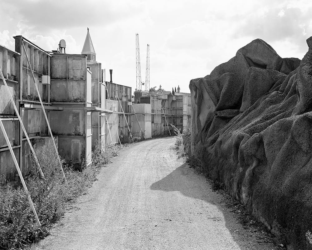 Black and white depiction of a narrow road, disappearing around the bend.
