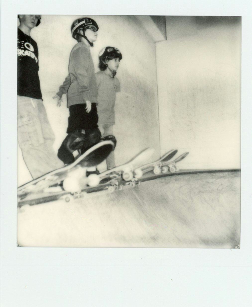 Polaroid BW of three skaters ready to jump off the ramp