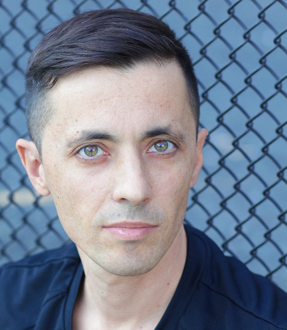 Portrait of the artist Paolo Cirio, in front of a wire fence. © Paolo Cirio