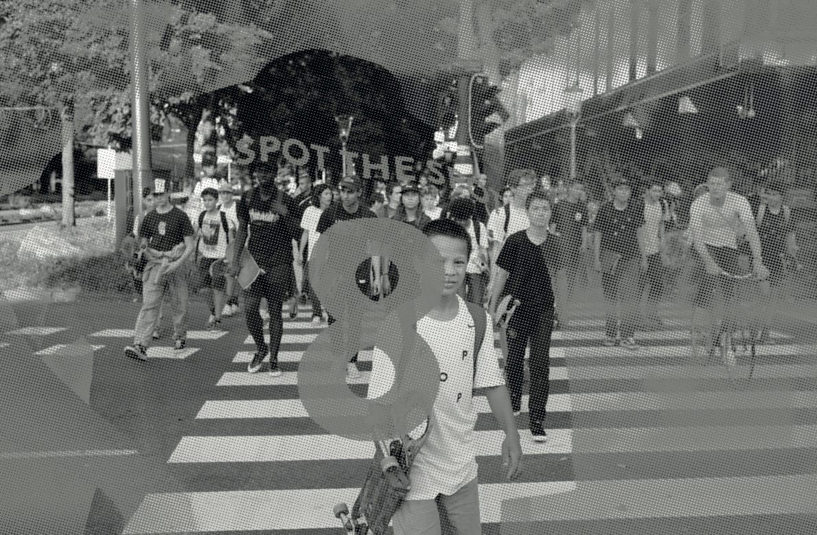 Black and white image of people on the street, with a boy and a skateboard in the front
