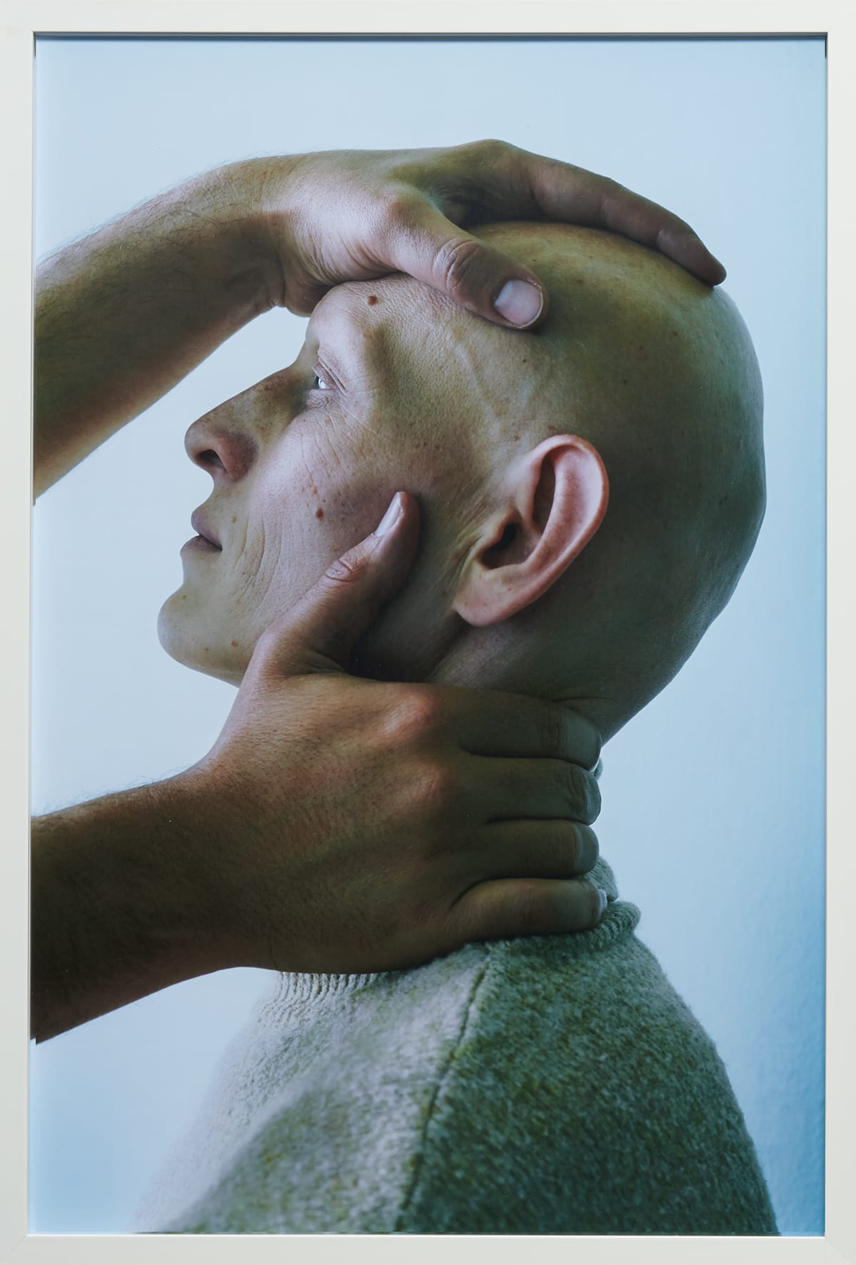 Staand portret van een kale man met handen op zijn hoofd en in zijn nek.