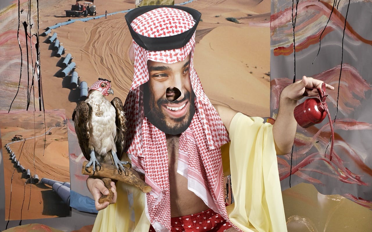 Person in traditional attire with a falcon and teapot, wearing a mask, in a desert setting with pipelines in the background.