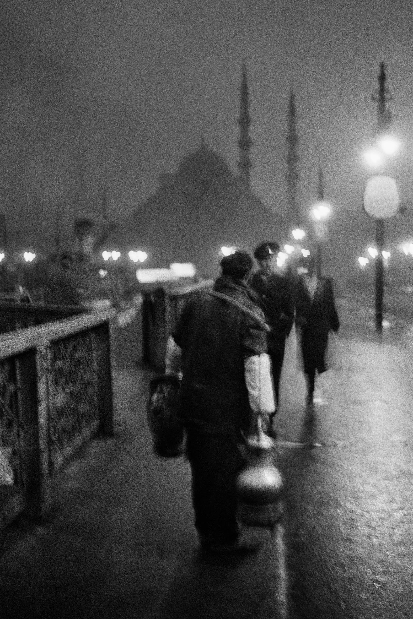 Black and white image of a street vendor at night on the Old Galata Bridge, in Istanbul. © Ara Güler