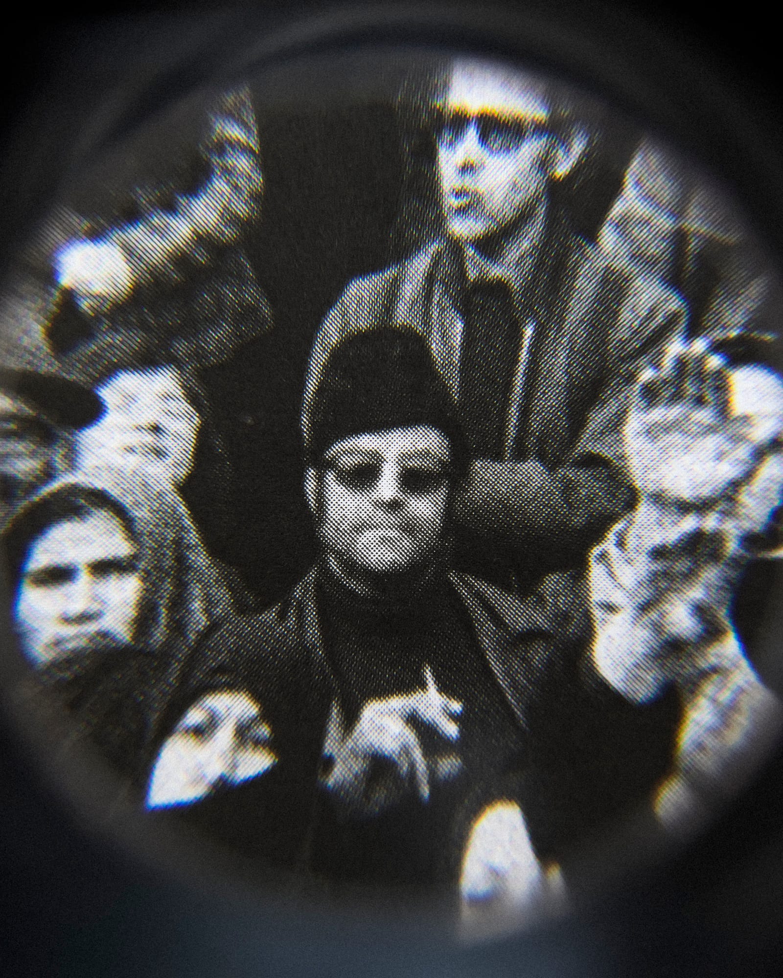 Black and white close-up image of an existing photograph, showing a man, wearing sunglasses and smoking a cigarette, staring into the camera in the middle of protesting crowd. Shot through a magnifying lens © Amin Yousefi© Amin Yousefi