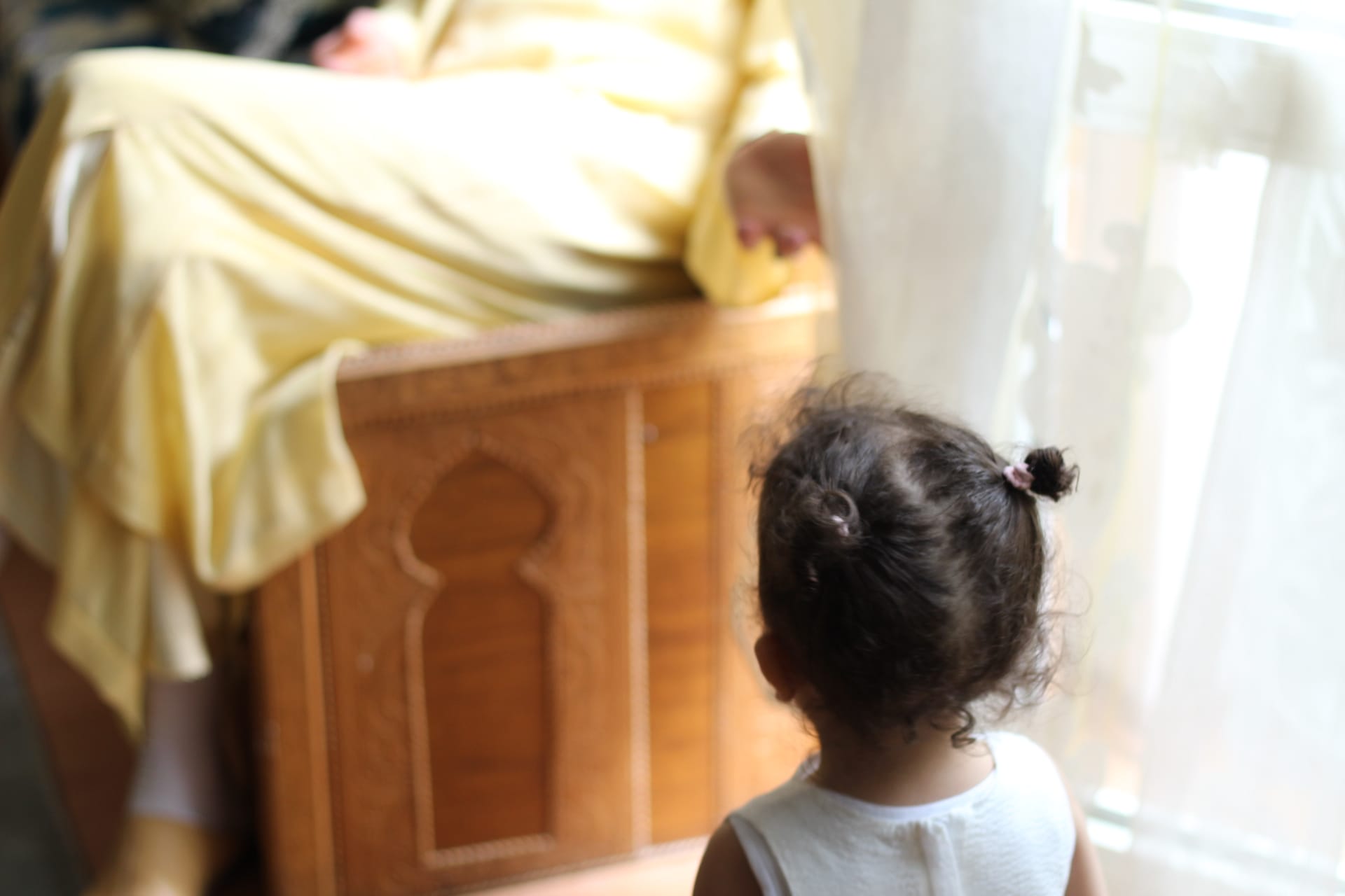 Photo of a young girl facing a seated person. © Dina Bousbaa