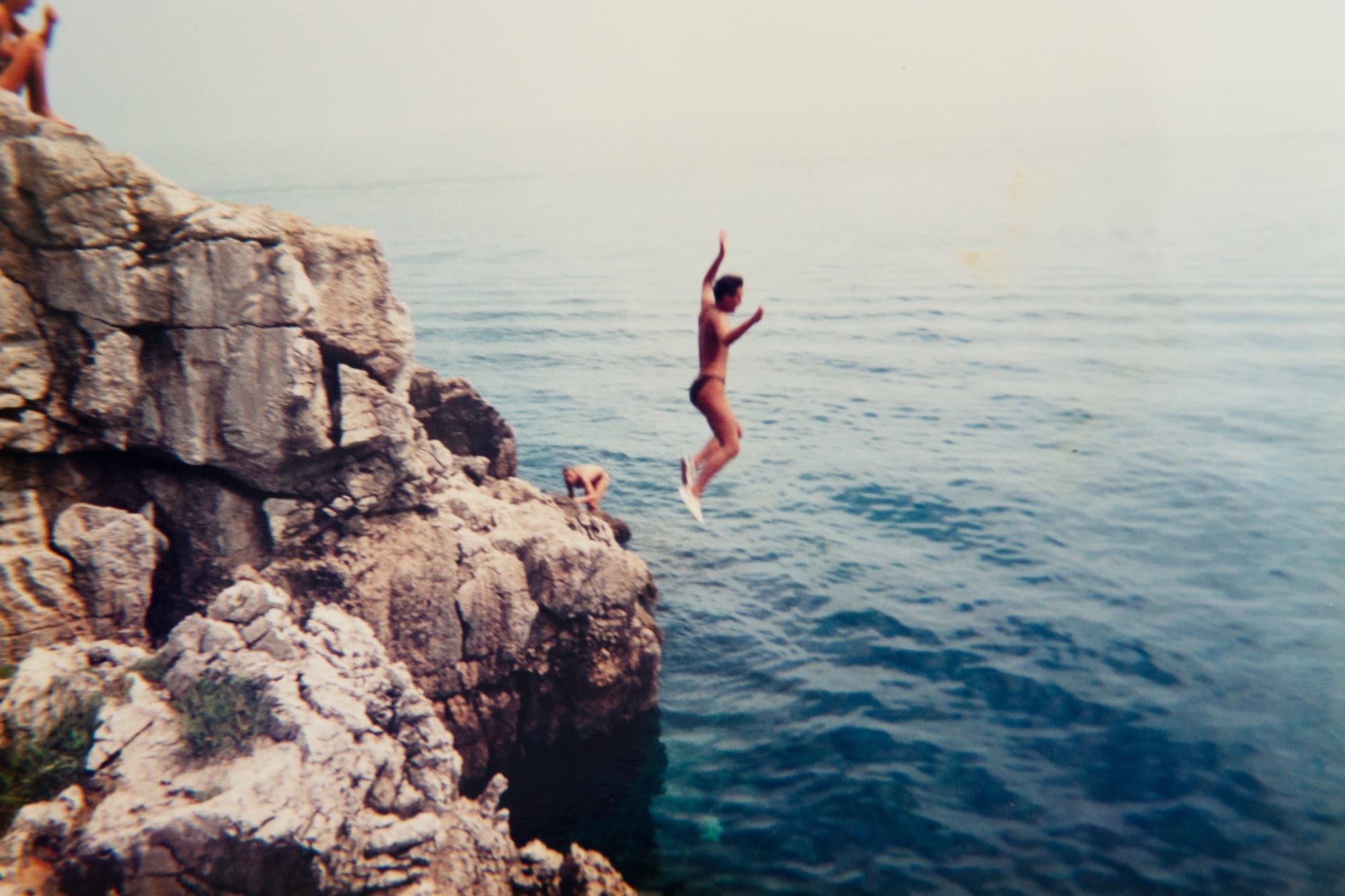 Archival holiday picture from the artist's personal archive, showing swimmers jumping into the ocean from a rock formation© Sander Coers