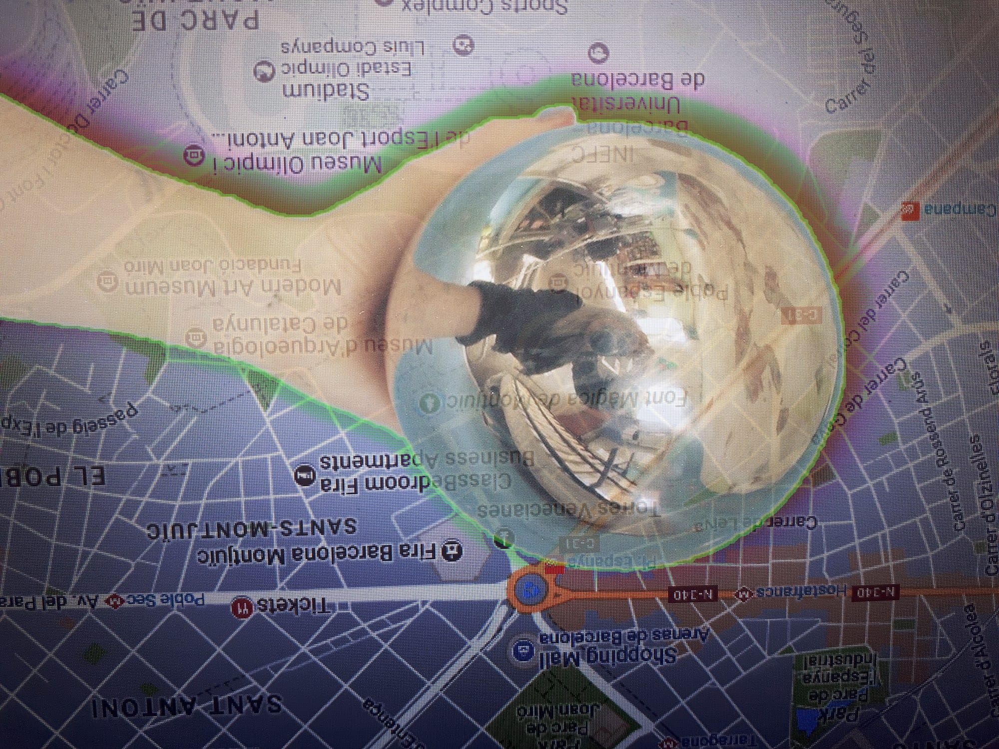 Collage of a hand holding a glass mirroring ball on top of the map of Barcelona. © Kıvılcım S Güngörün