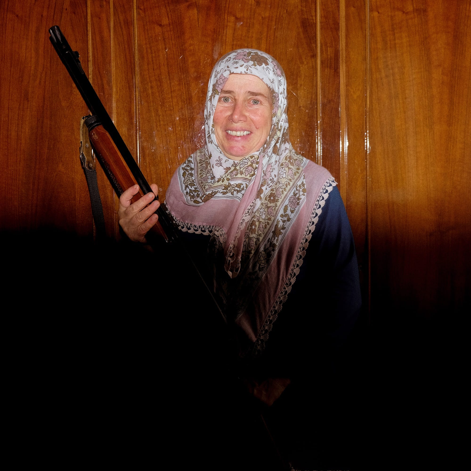 Portrait of a woman wearing a patterned head scarf and a rifle. © Cansu Yıldıran