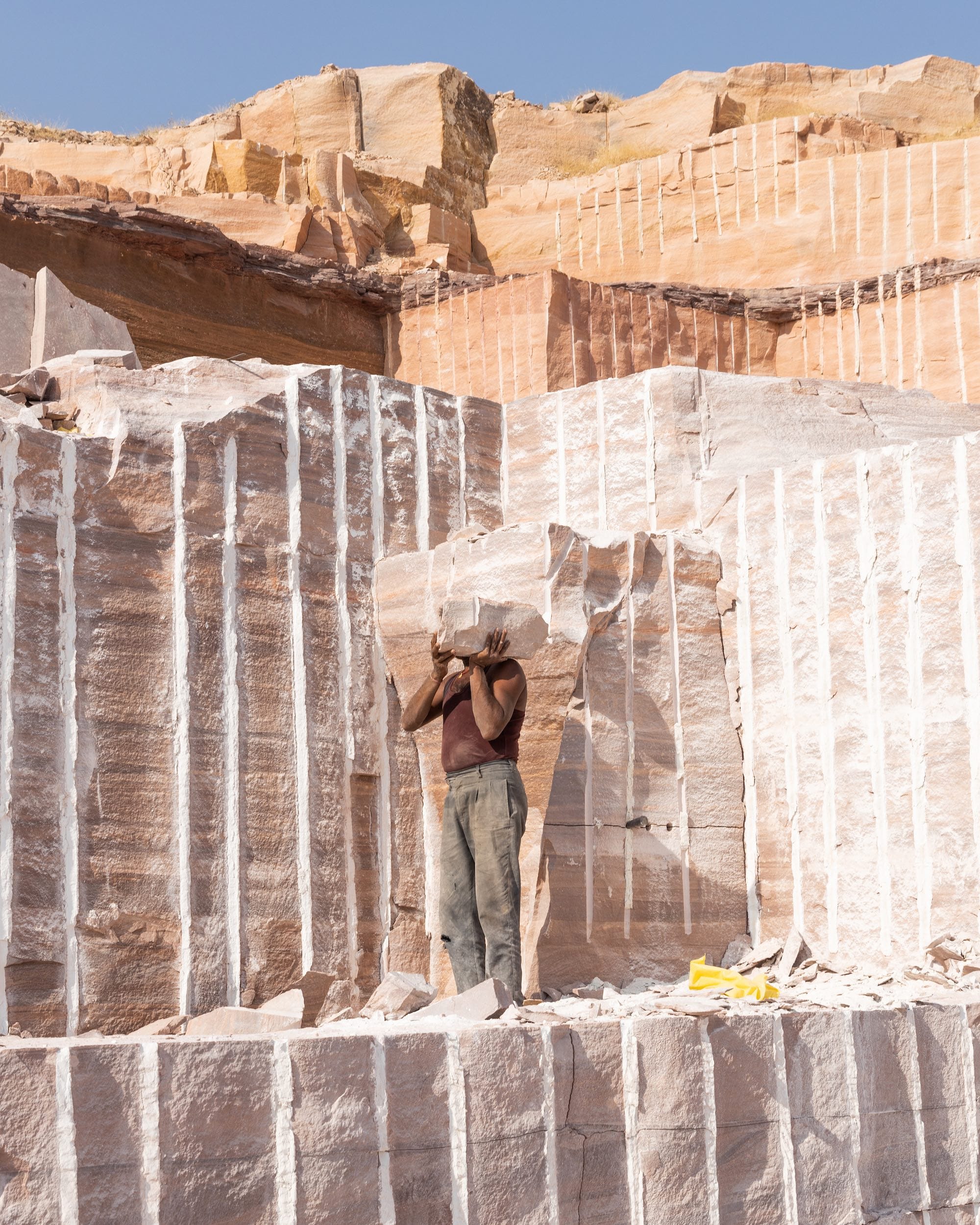 Portrait of a topless man, holding a block of sand in front of his face, inside a sandstone © Aaryan Sinha