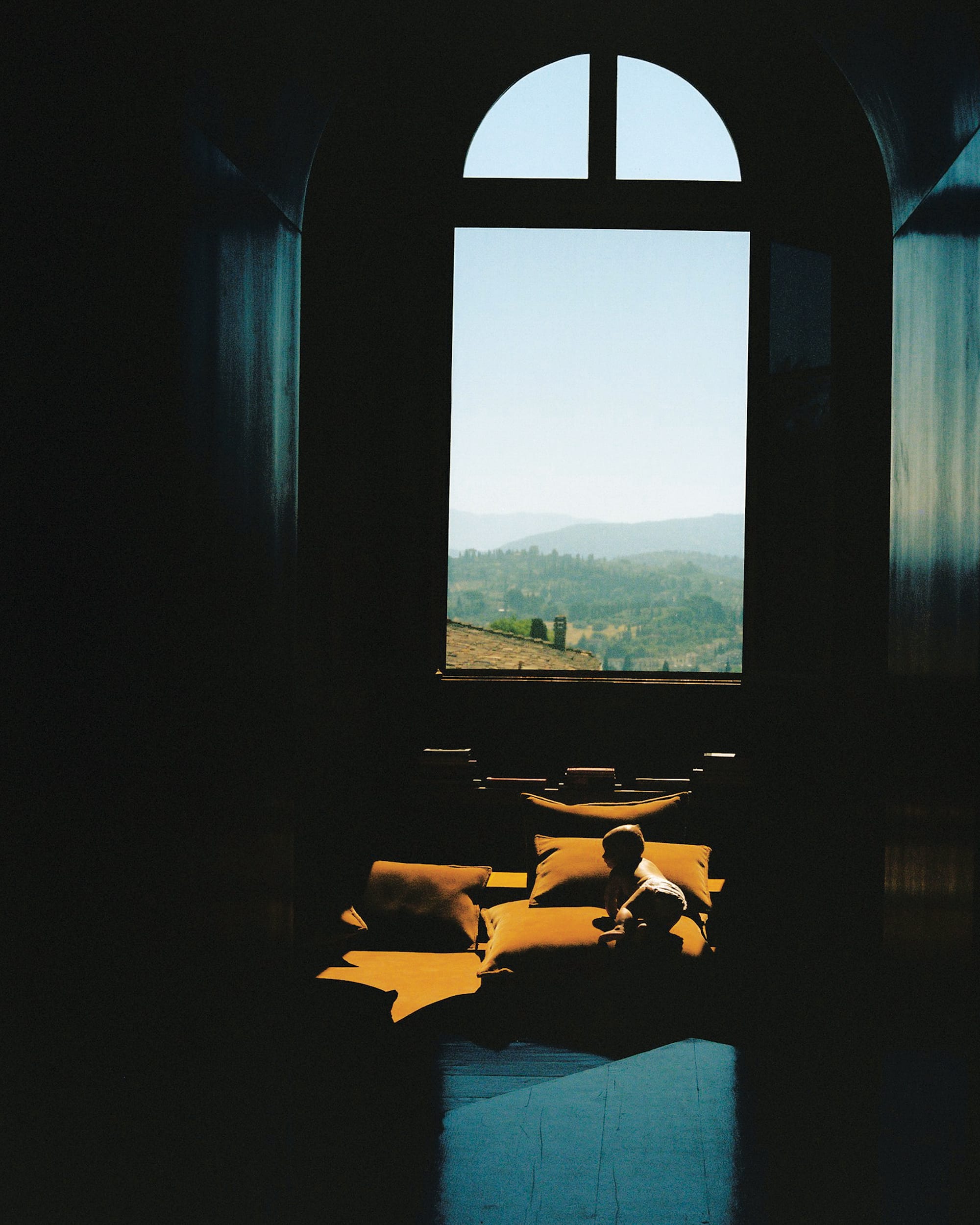 baby on a yellow sofa and a view on a hilly landscape