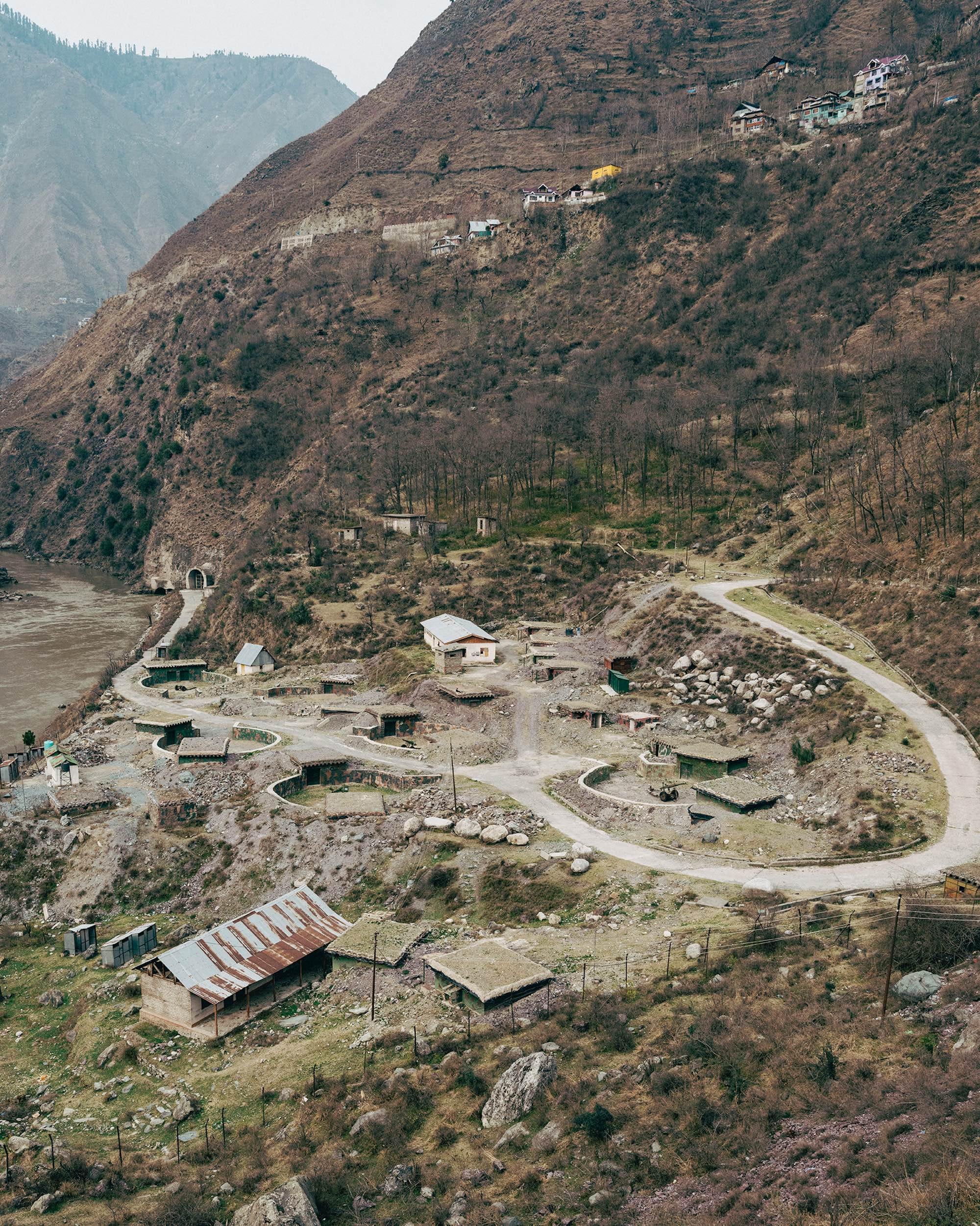 Aerial view of a mountain slope with a winding road and scattered buildings in the Uri region in Kashmir © Aaryan Sinha