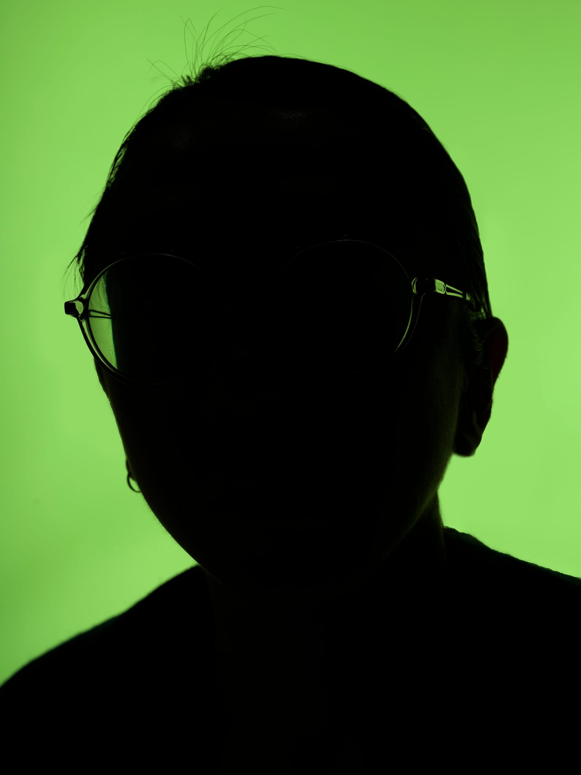 Self portrait of the artist, only showing the outline of the face in front of a green background. © Sheung Yiu