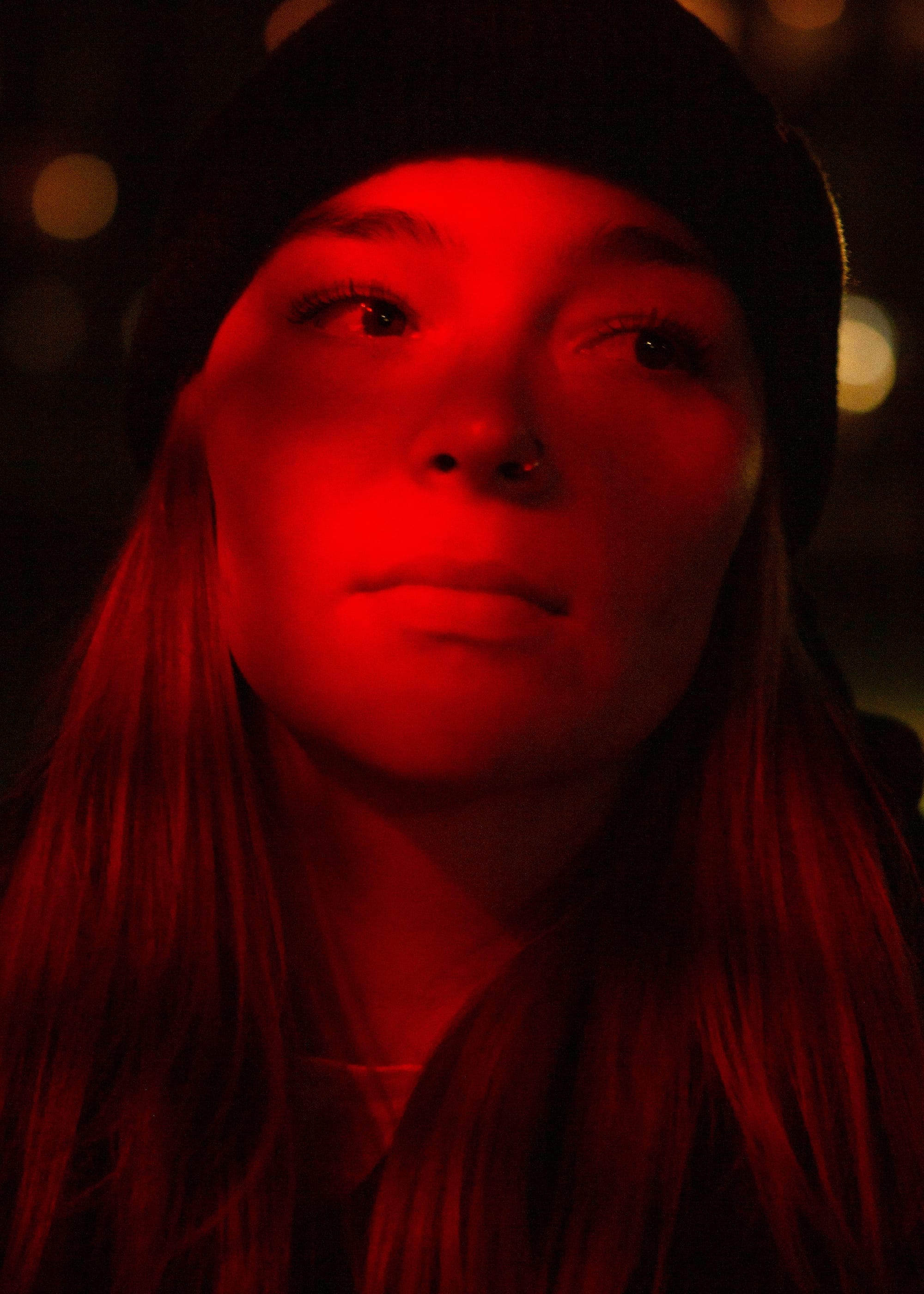 portrait of a person with a red light over them, looking away from the camera