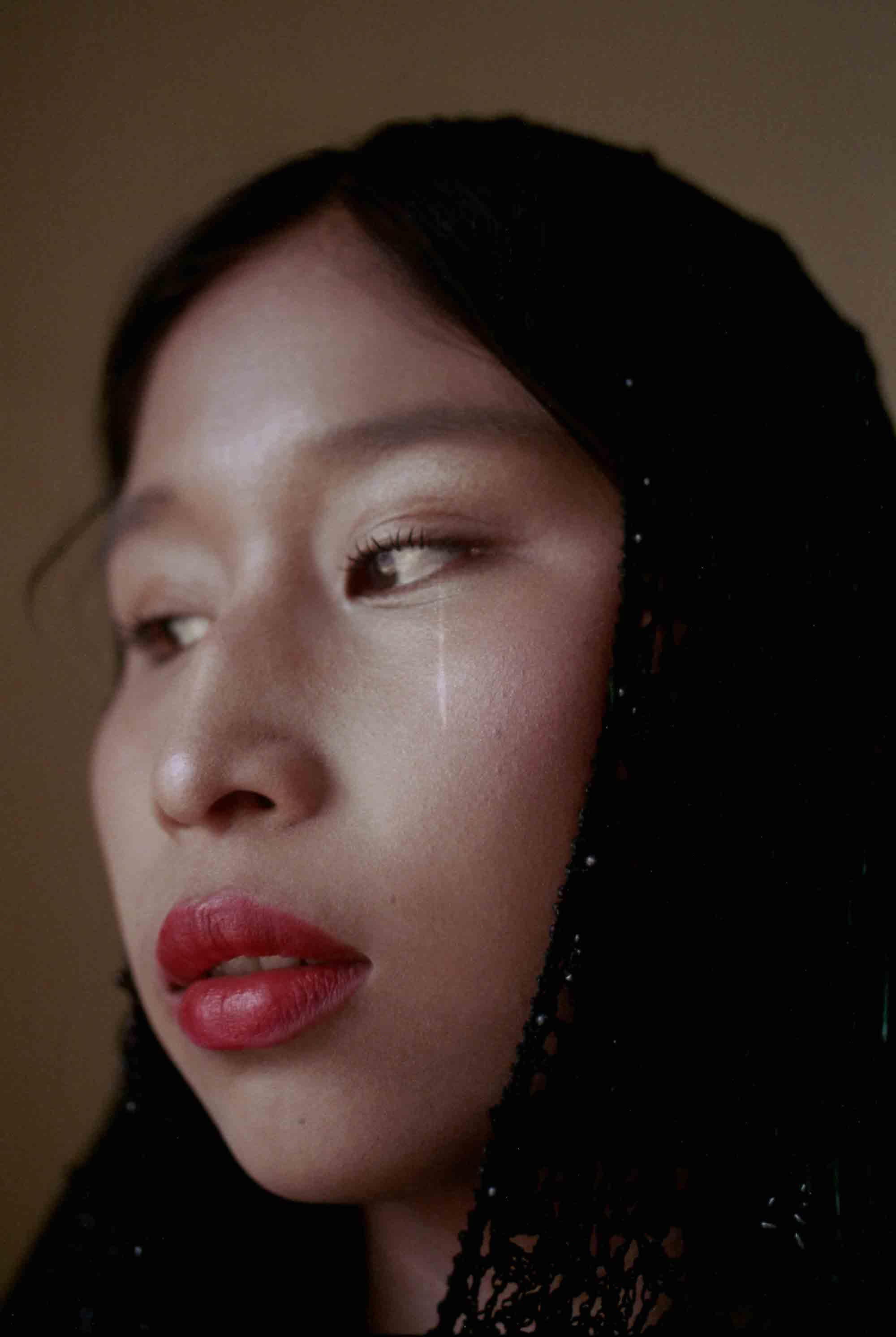 Portrait of a woman wearing red lipstick and a black veil. © Marisol Mendez