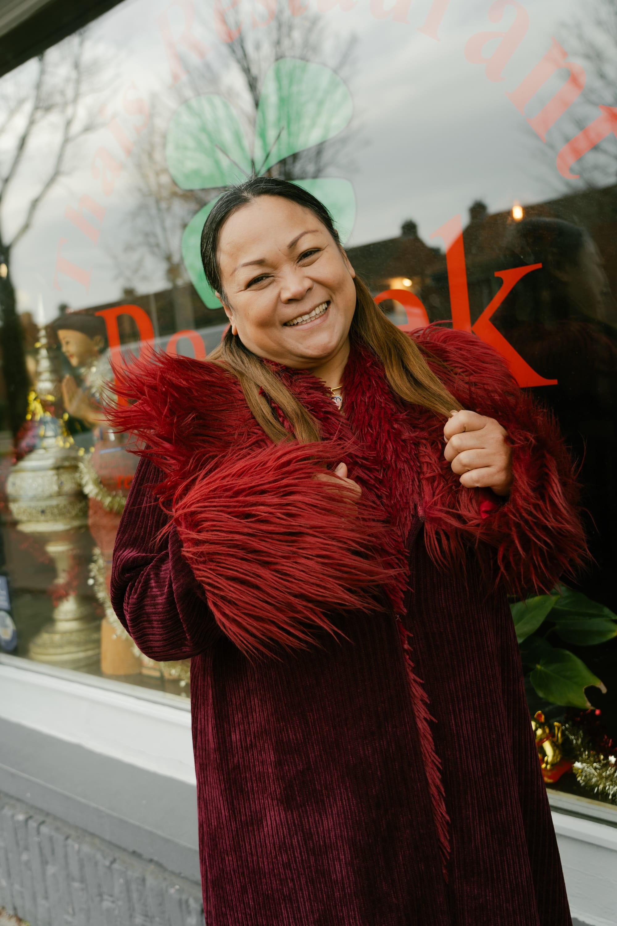 Person laughing in the camera with a red dress, outside on the street.