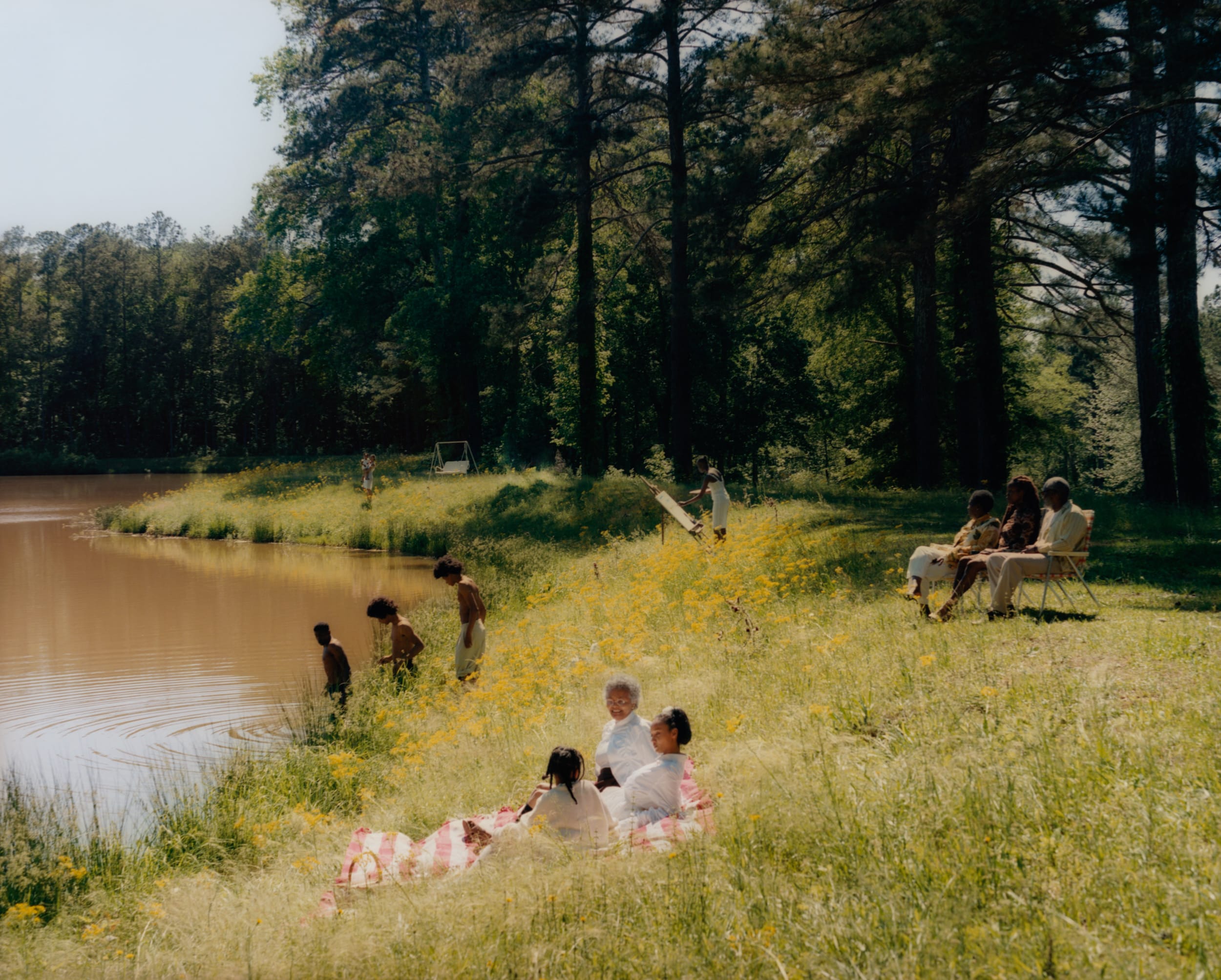 Families and young people laying on the grass by a river