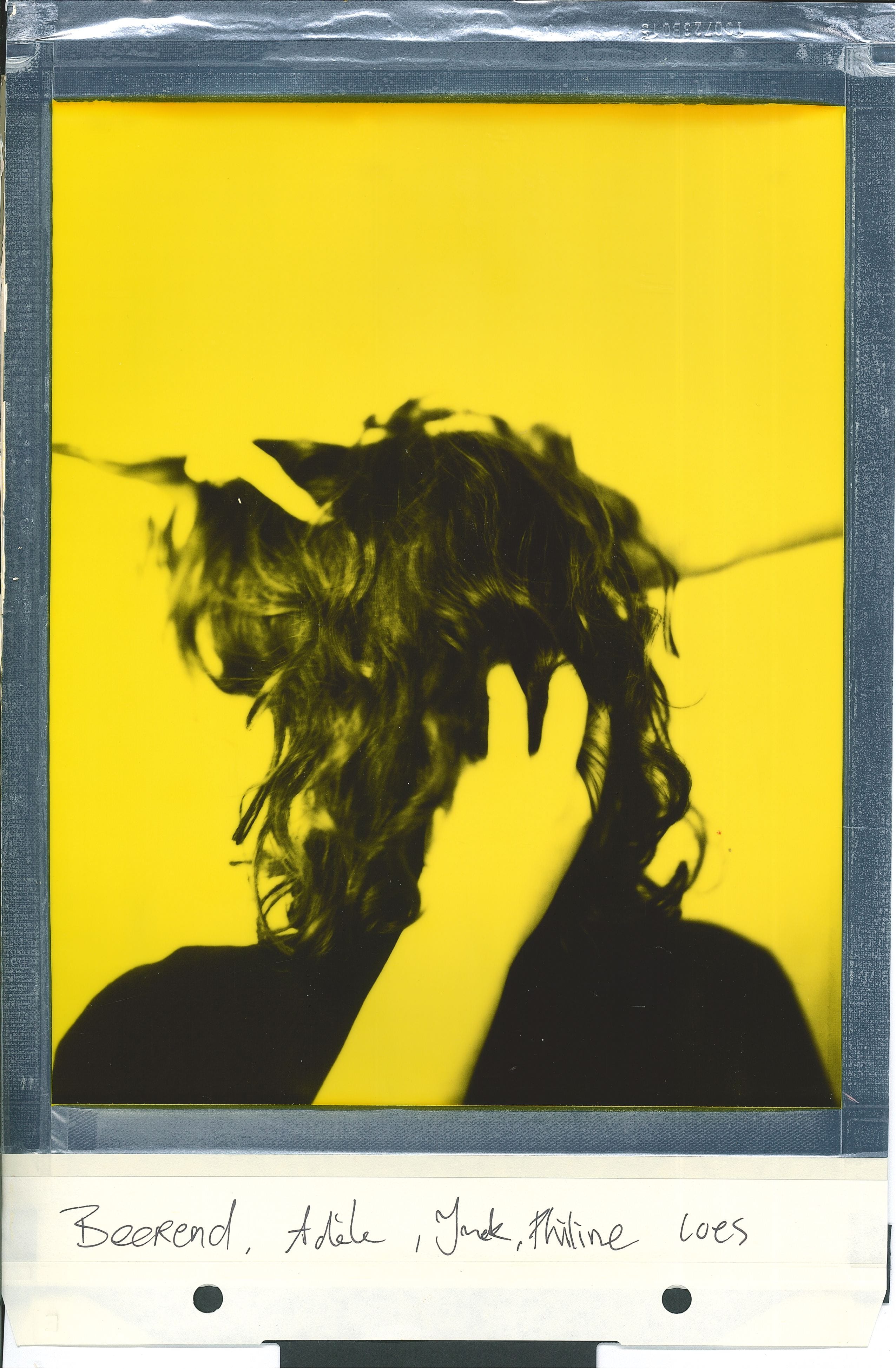 Polaroid portrait turned around woman hands touching hair yellow