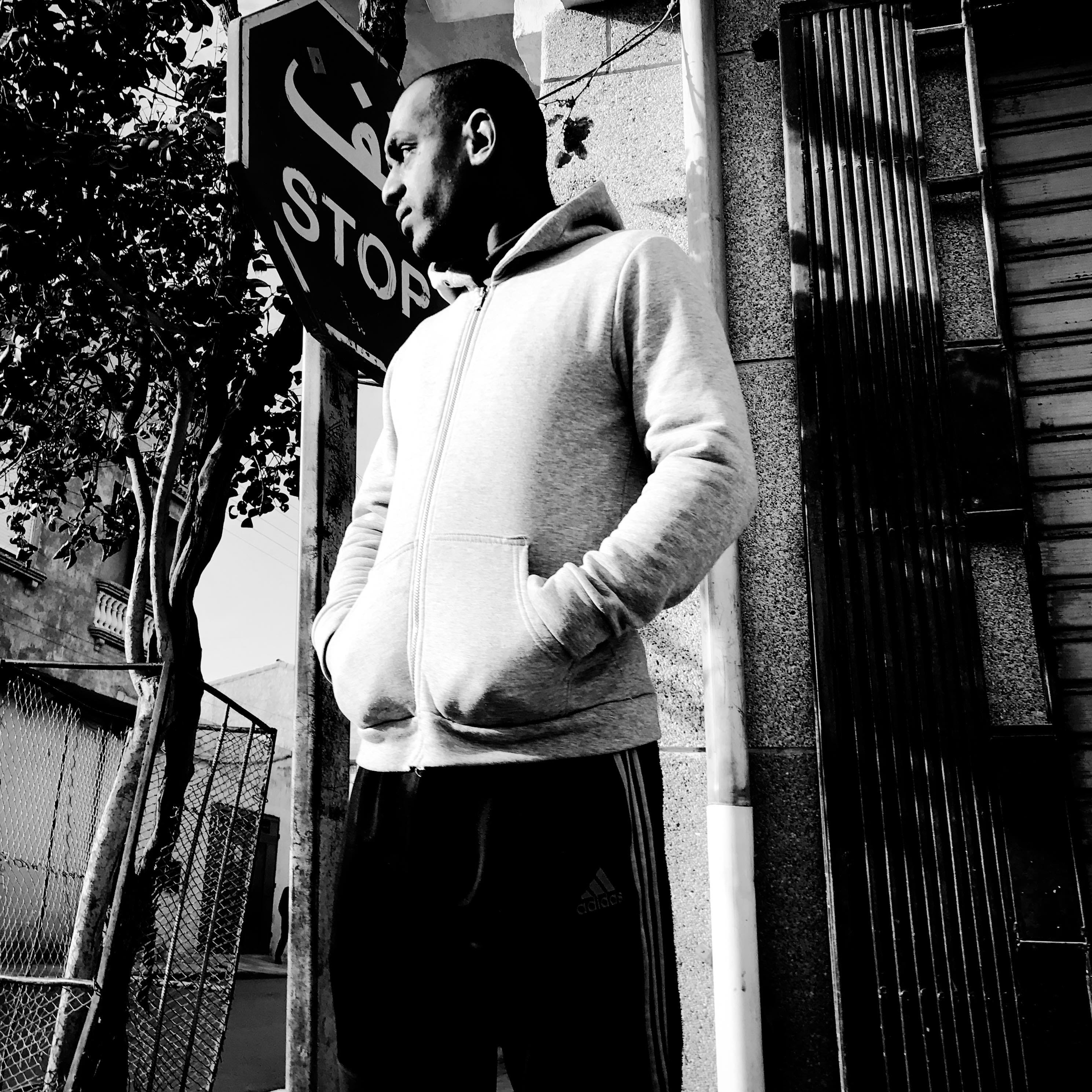 Black and white portrait of a man in front of a traffic sign. © Issam Larkat