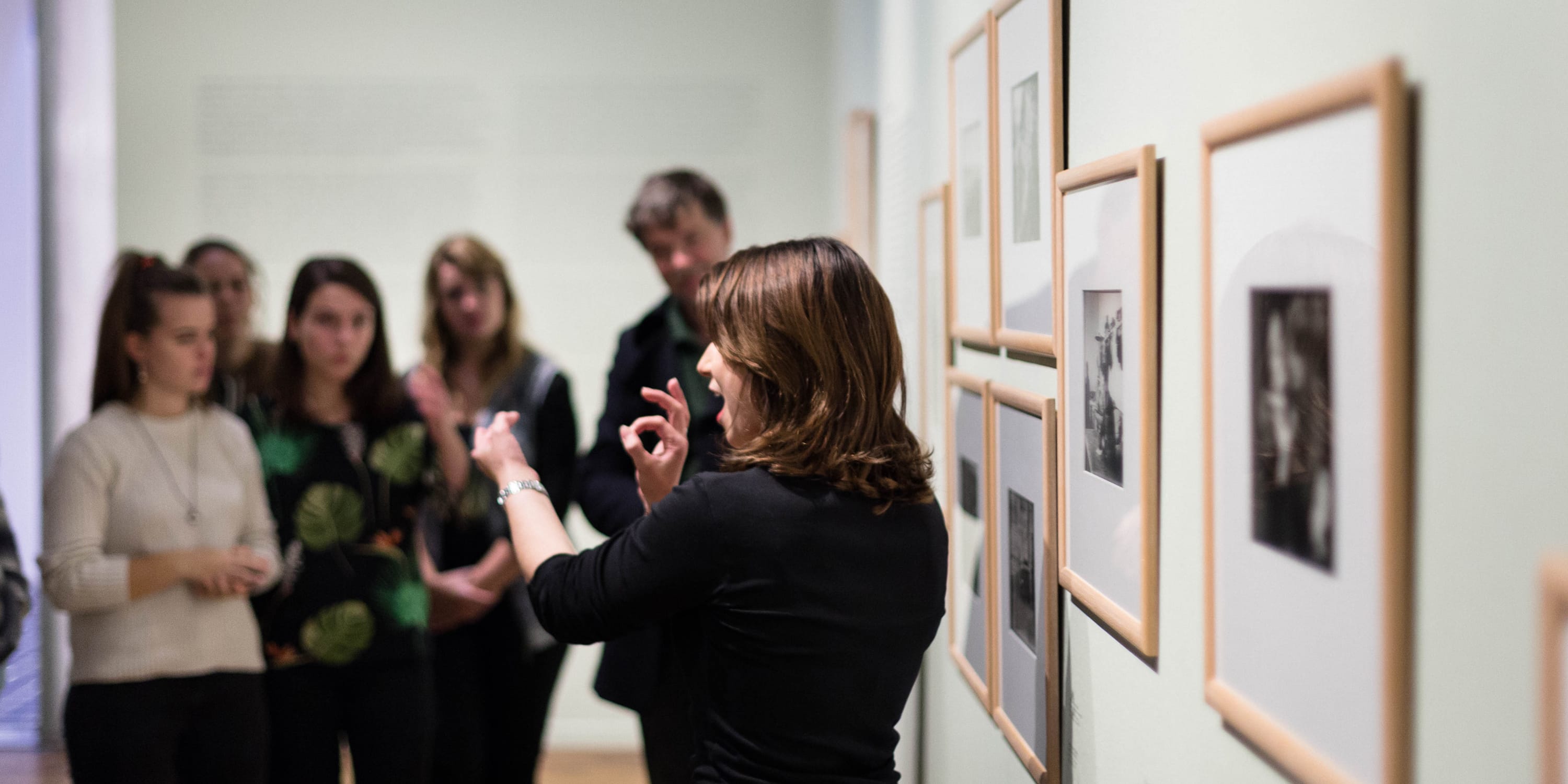 Female presenting person giving a tour in sign language in a museum.