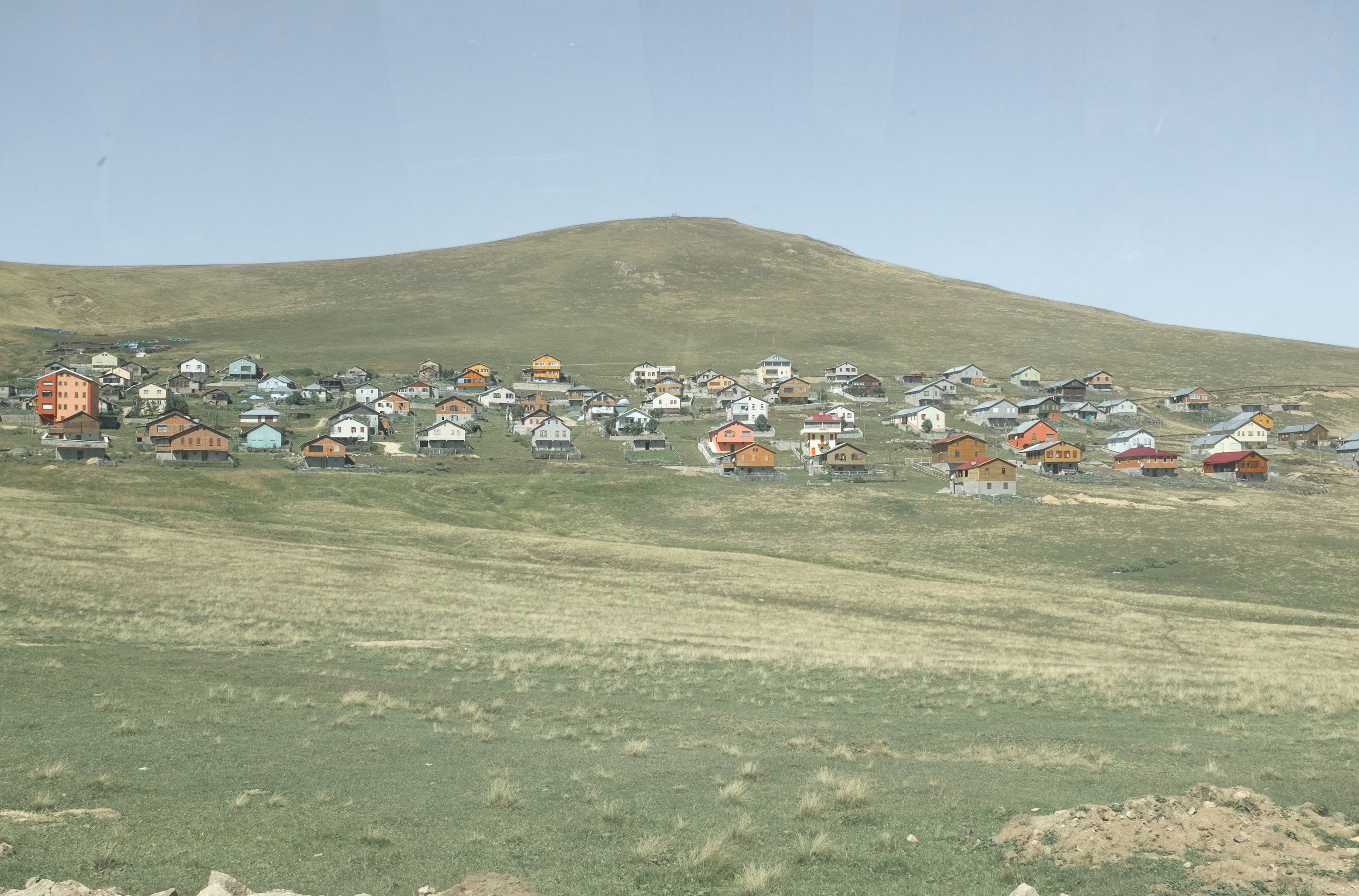 Landscape photo of a village in the Kushmer Highlands in Turkey on a green hill. © Cansu Yıldıran