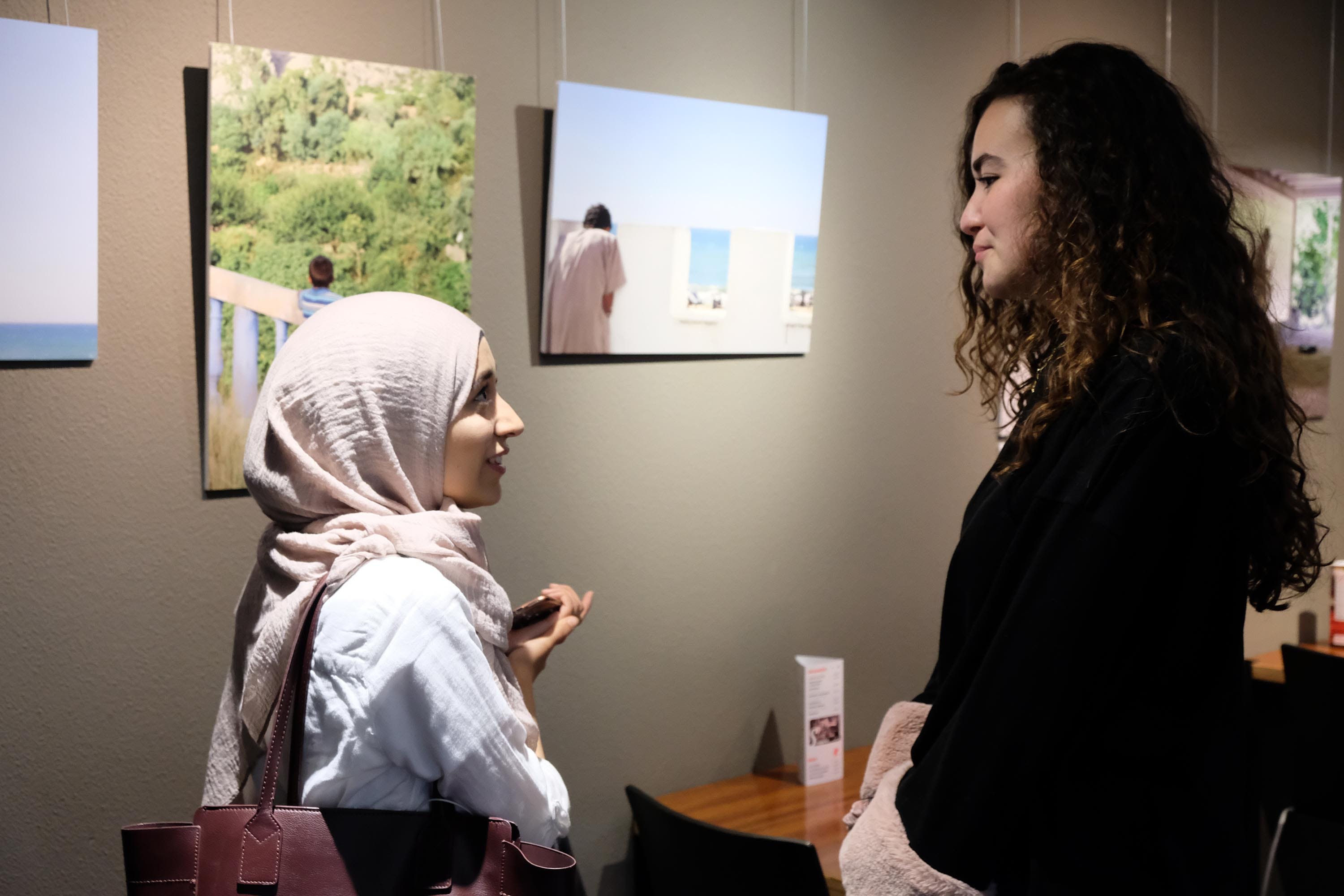 Two women have a discussion inside an exhibition.