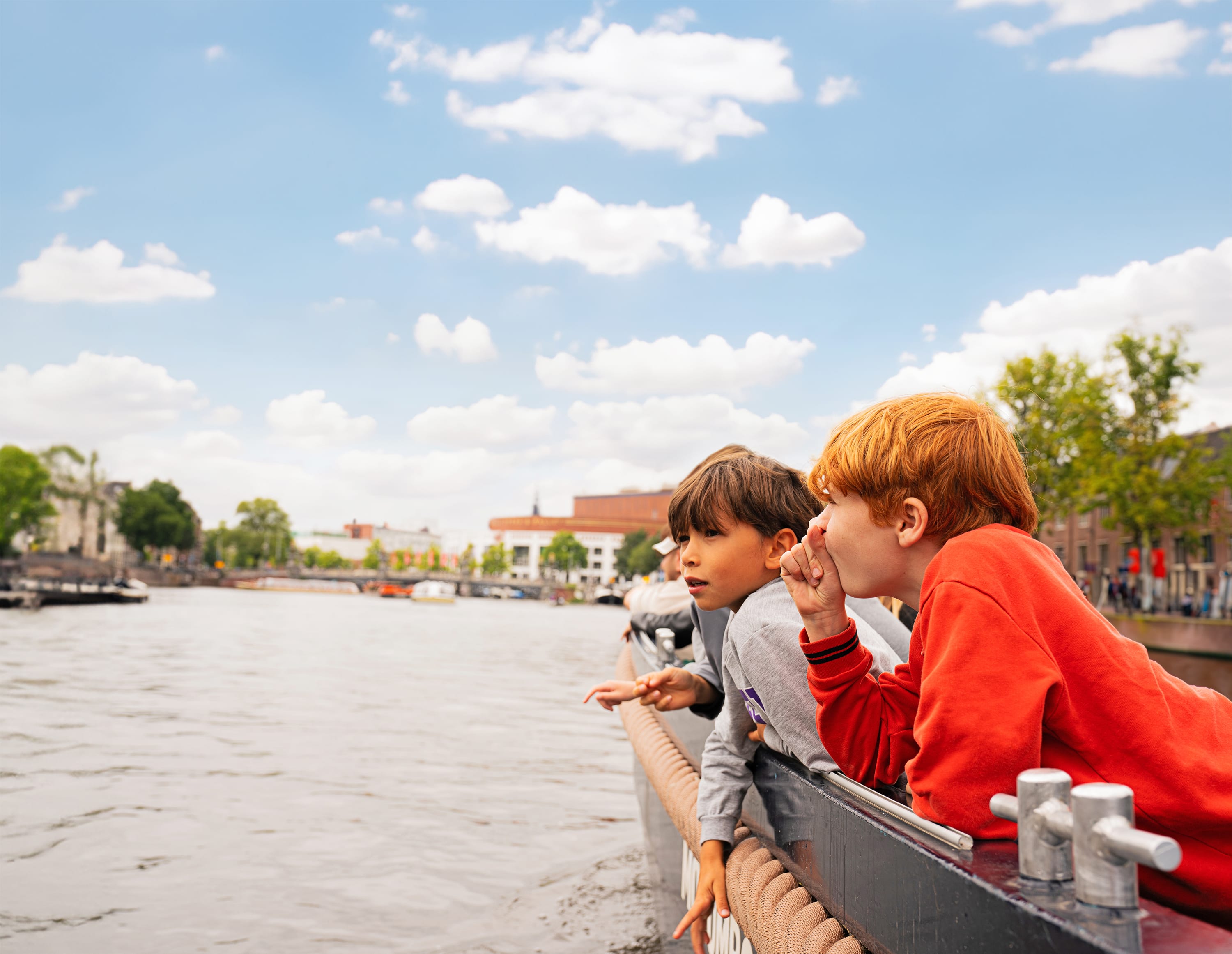 boys in a boat looking over the canal