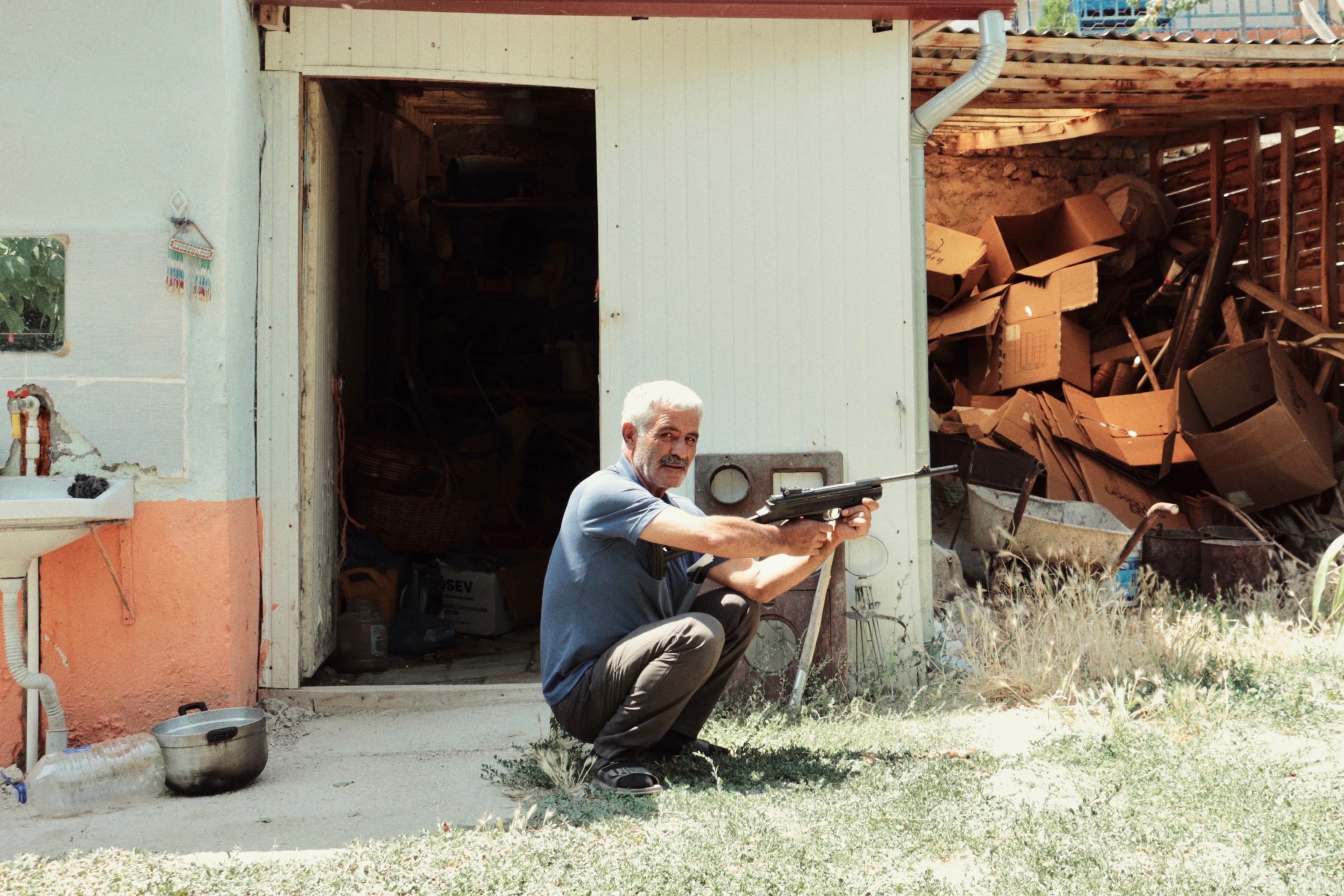 My uncle playing with his air rifle in front of my grandparents' house in Yeşildere. This is where my father spent the first ten years of his life. © Yasemin Demirözcan
