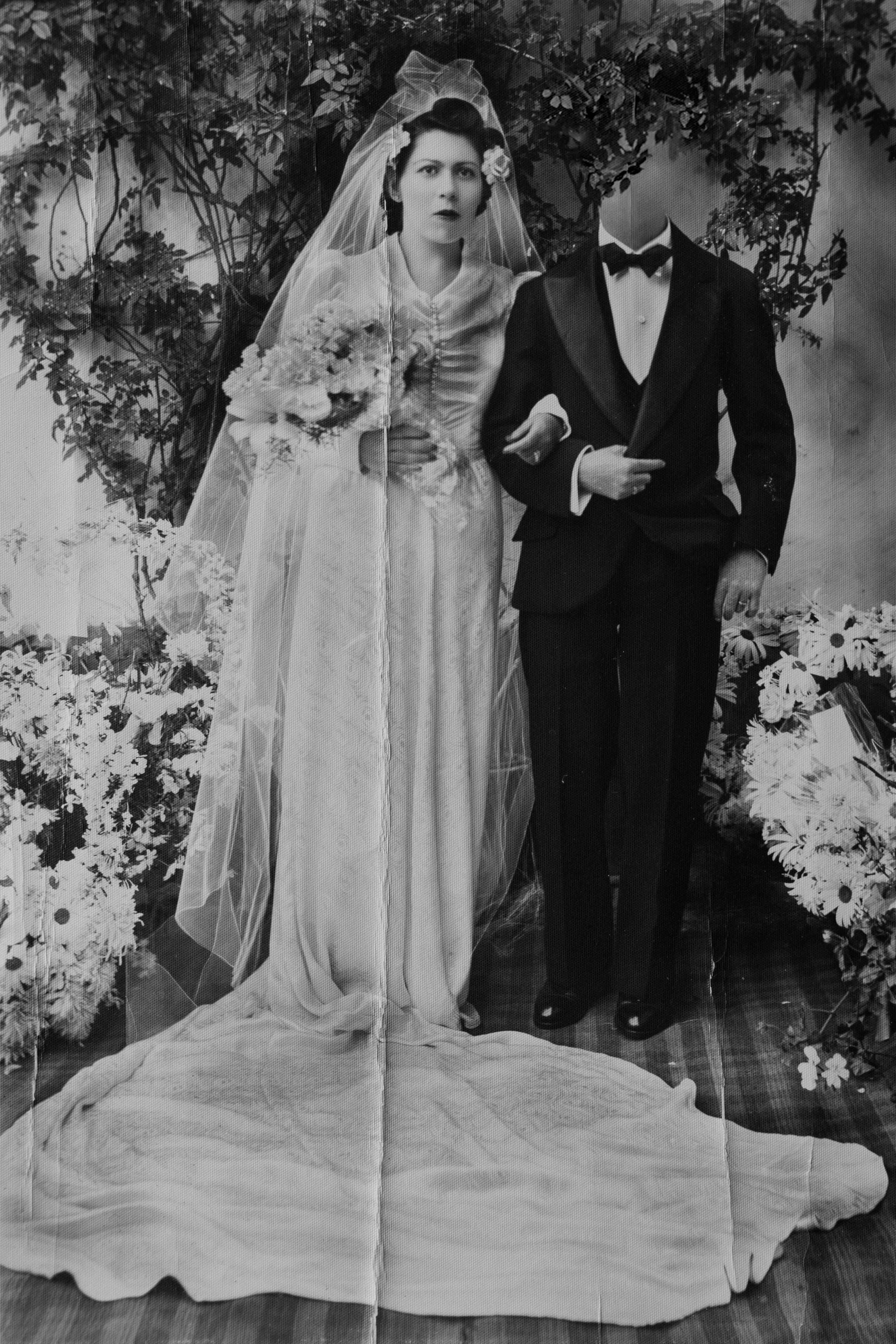 Archival image of a married couple, where the head of the groom is faded out. © Marisol Mendez