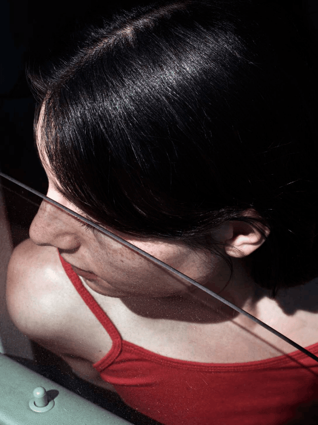 A close-up from a woman wearing a red tanktop, sitting in a car