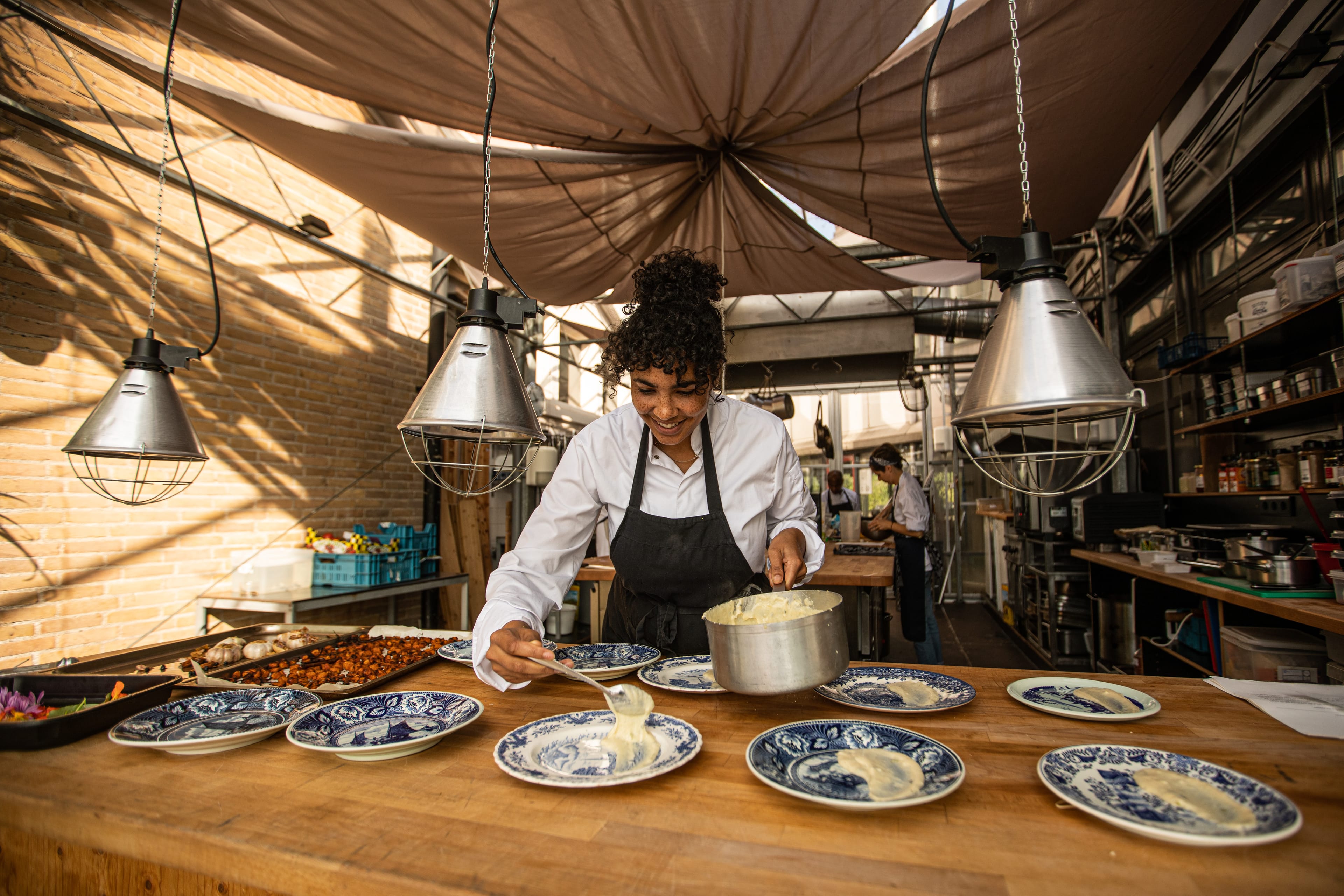 Female presenting person cooking a dinner in a tent looking environment.