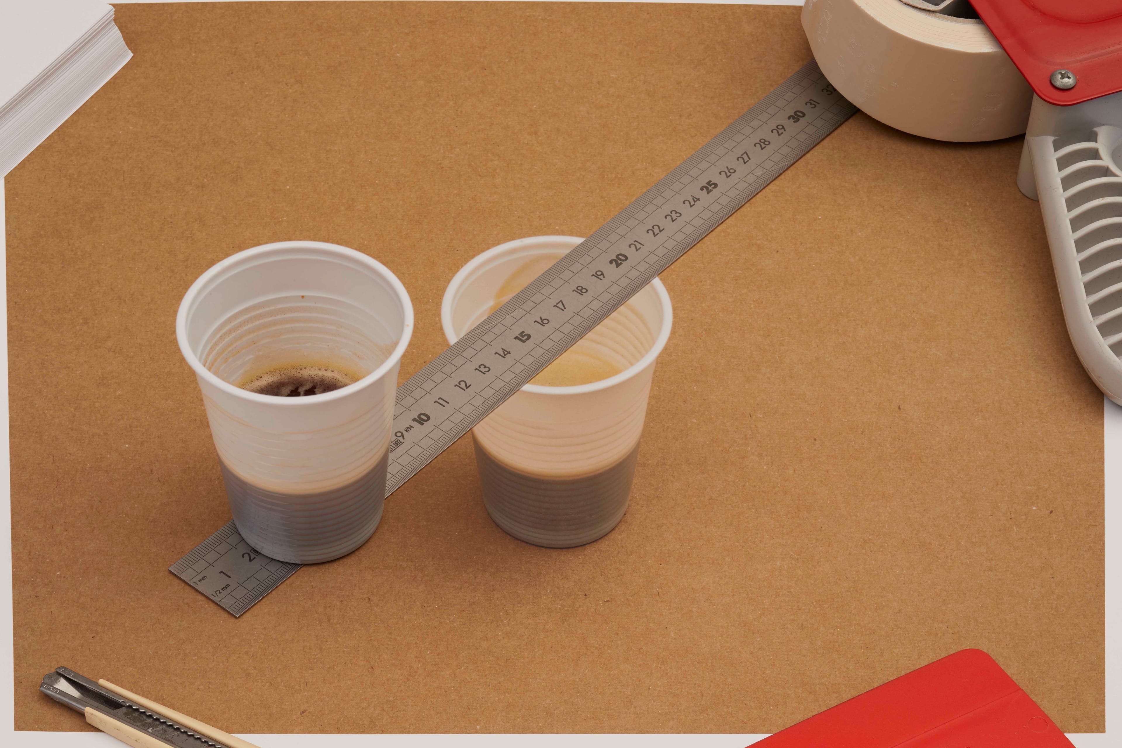 two cups of coffee with a metal ruler