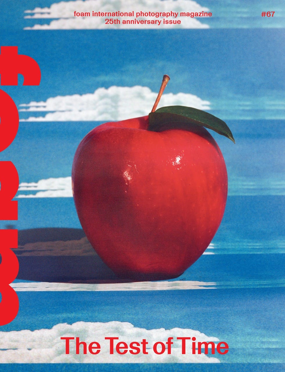 A shiny red apple with a green leaf against a blue sky with clouds, featured on the cover of a photography magazine.