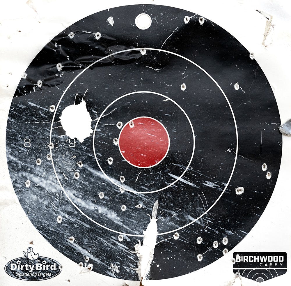 Black worn down gun target, with red center and bullet holes © Jaclyn Wright
