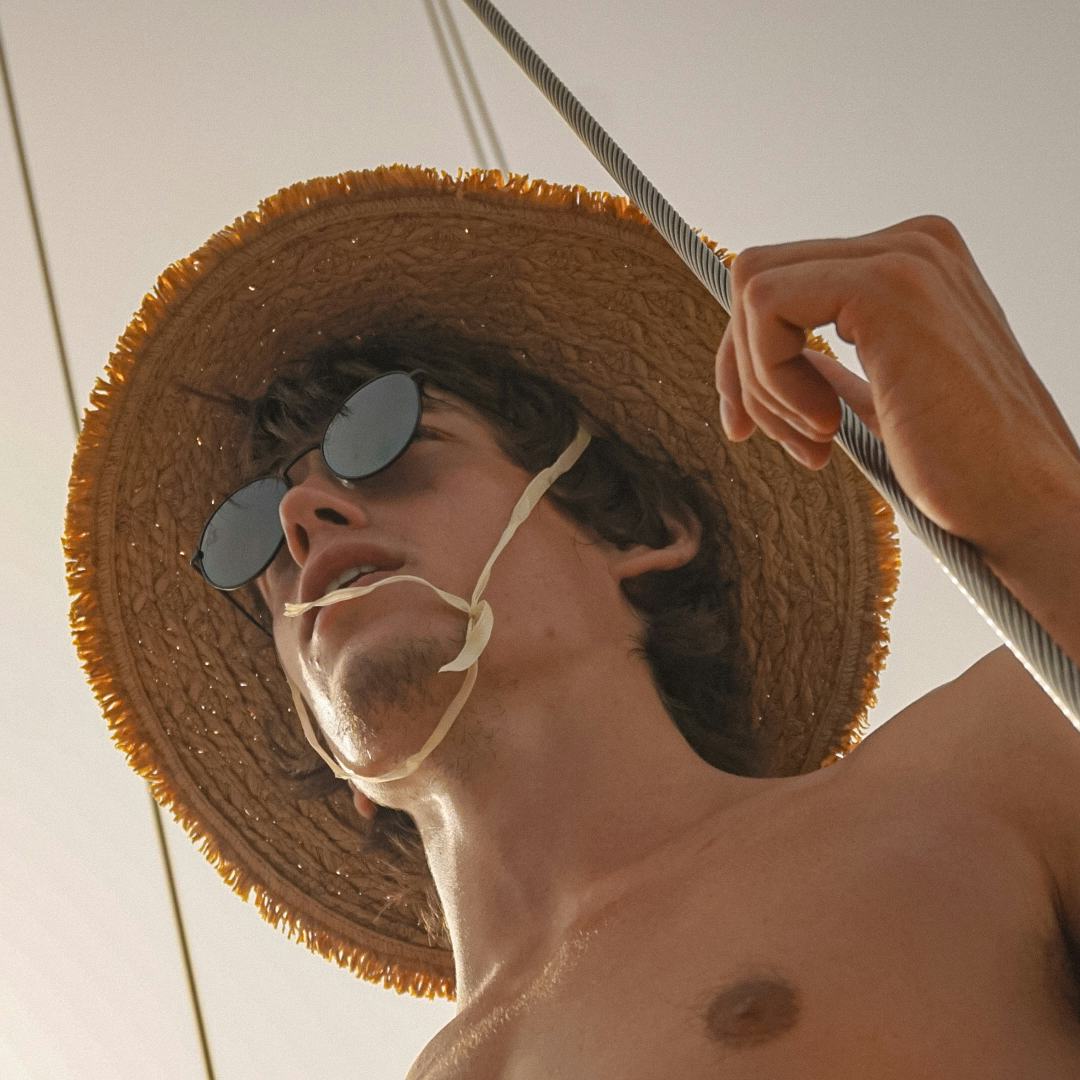 Portrait of a young white man with a straw hat and sunglasses. © Tal Ben Yakir