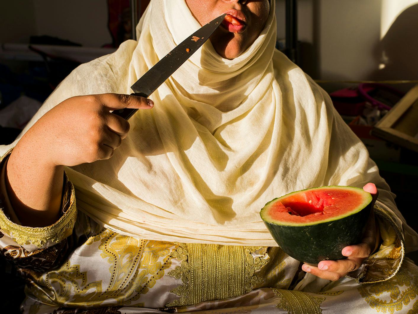 woman licking knife with watermelon in hand