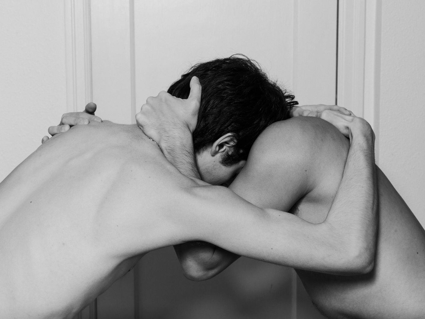 Black and white image of two undressed people wrestling. Only their bare backs, arms and hands are visible, as well as the head of one of them. © Ricardo Nagaoka