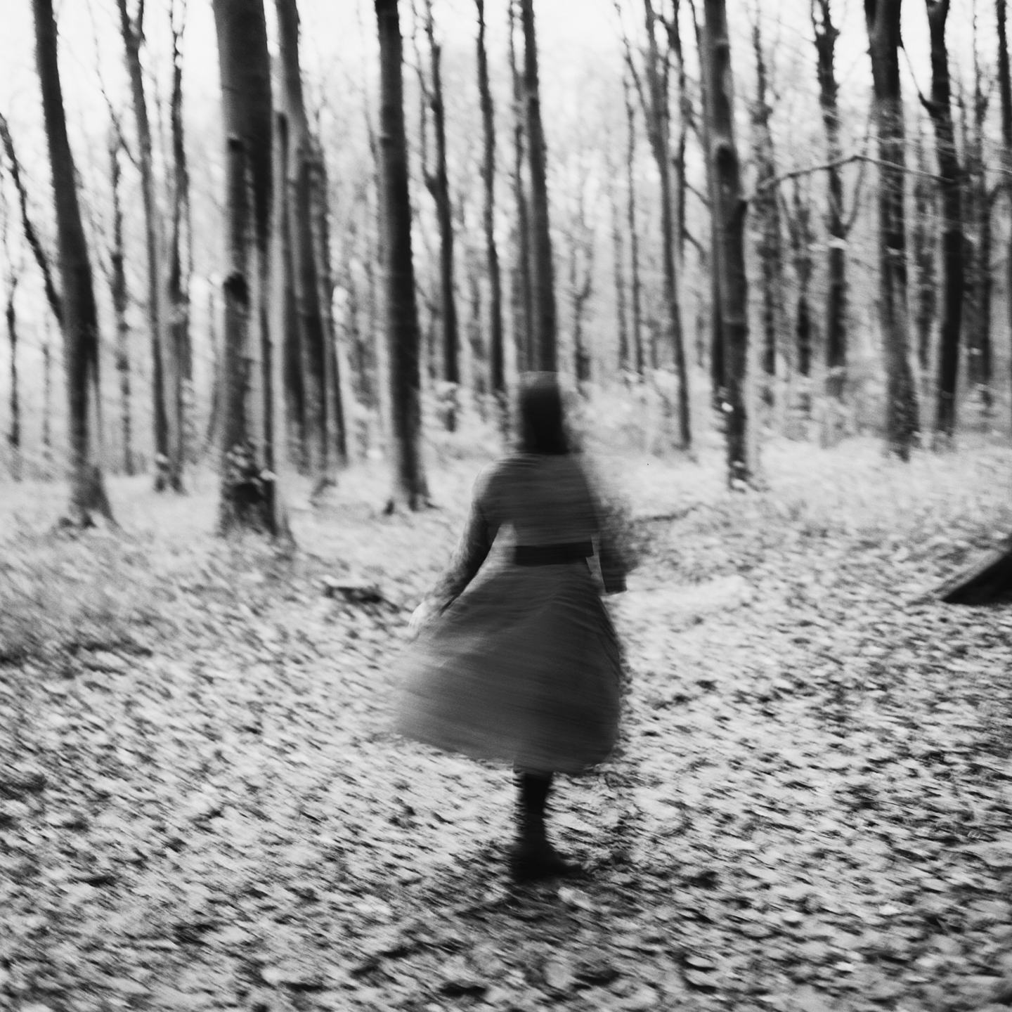 Black and white image of a blurred woman walking in the forrest