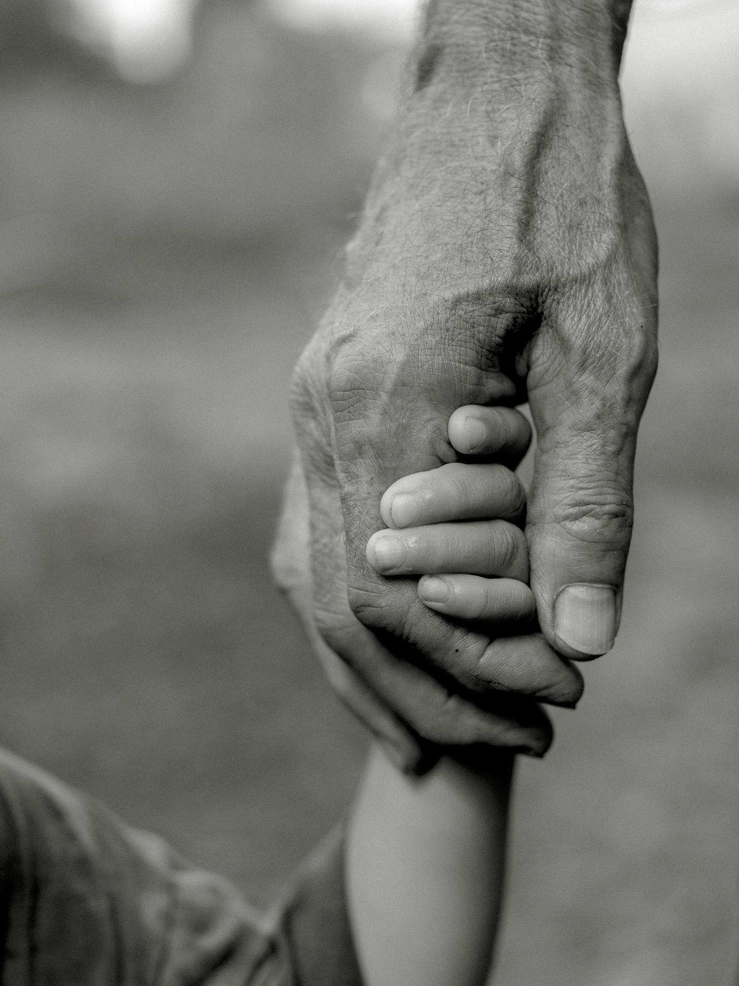 Black and white image of a person holding a kids' hand