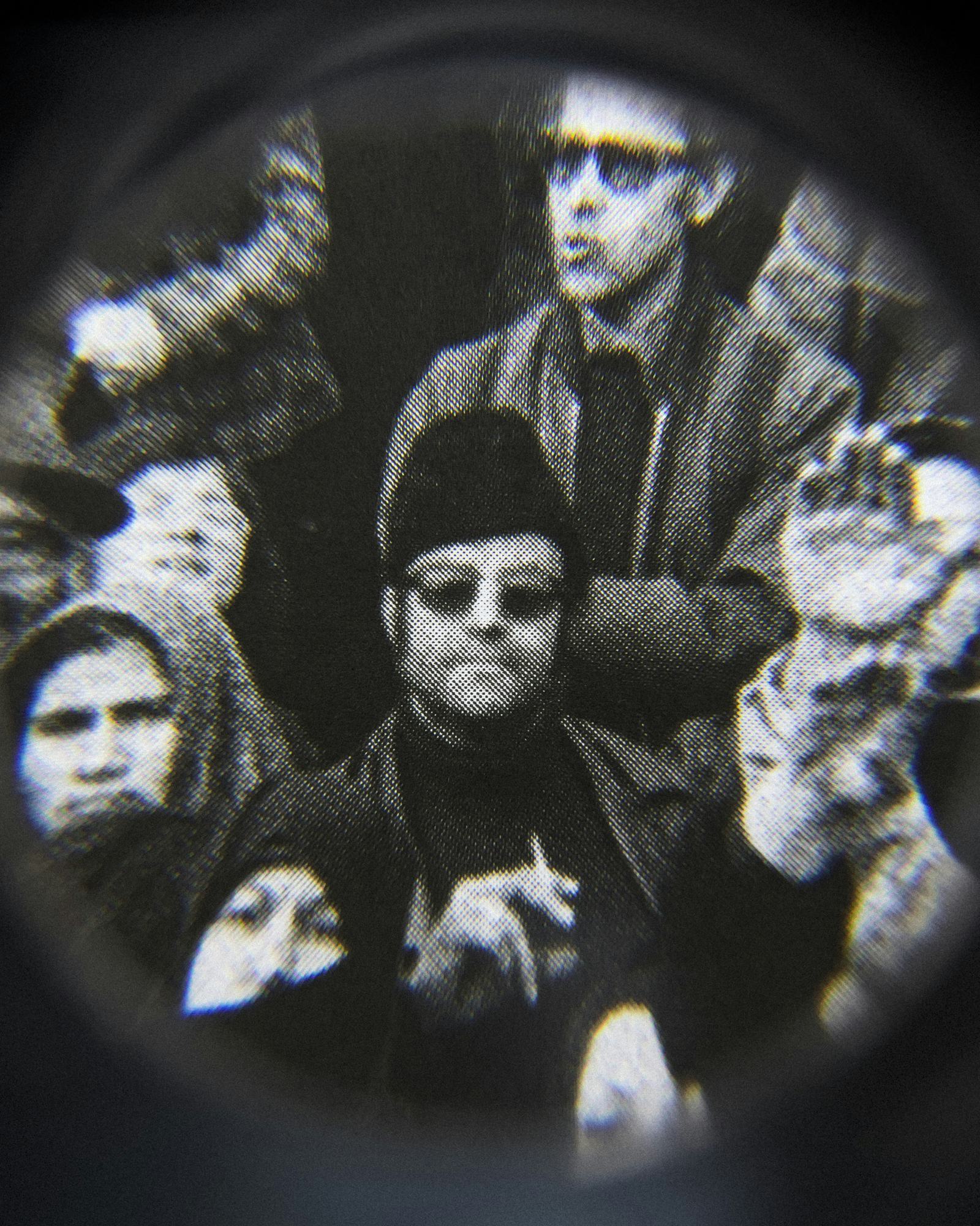 Black and white close-up image of an existing photograph, showing a man, wearing sunglasses and smoking a cigarette, staring into the camera in the middle of protesting crowd. Shot through a magnifying lens © Amin Yousefi© Amin Yousefi
