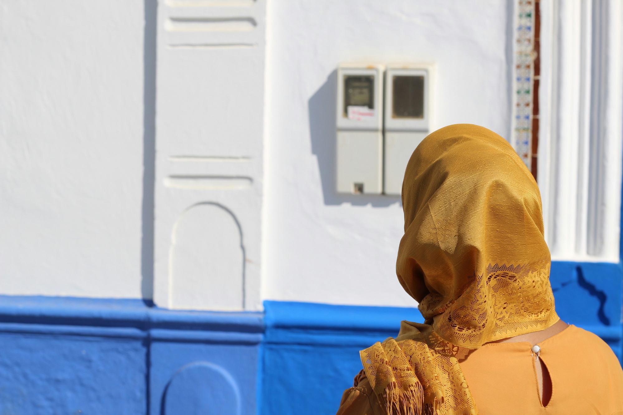 Photo of a woman wearing a yellow hijab looking at a wall
