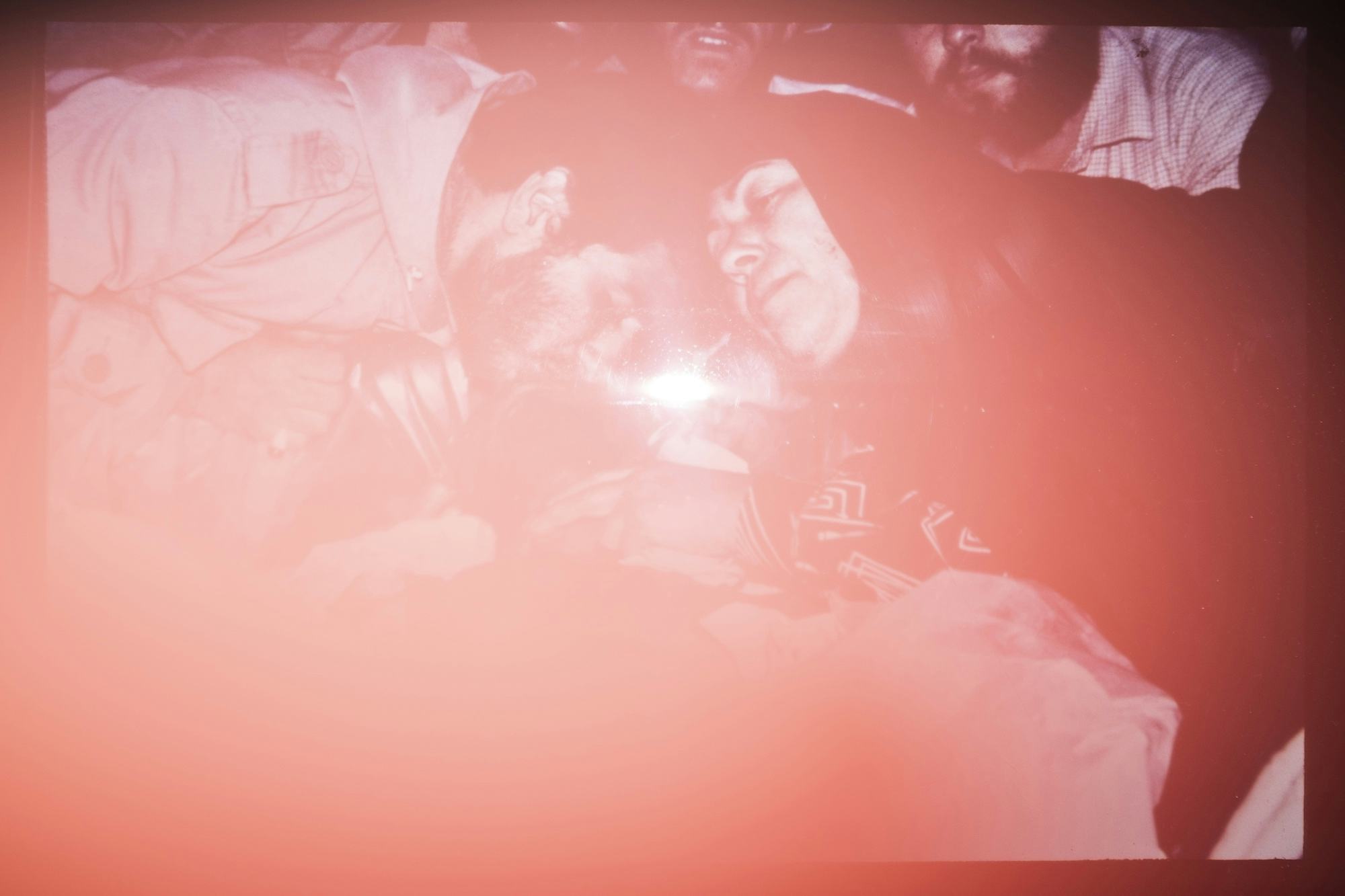 Photograph of an Iranian woman and man in mourning, the image has a red filter due to the flash. © Ghazaleh Rezaei