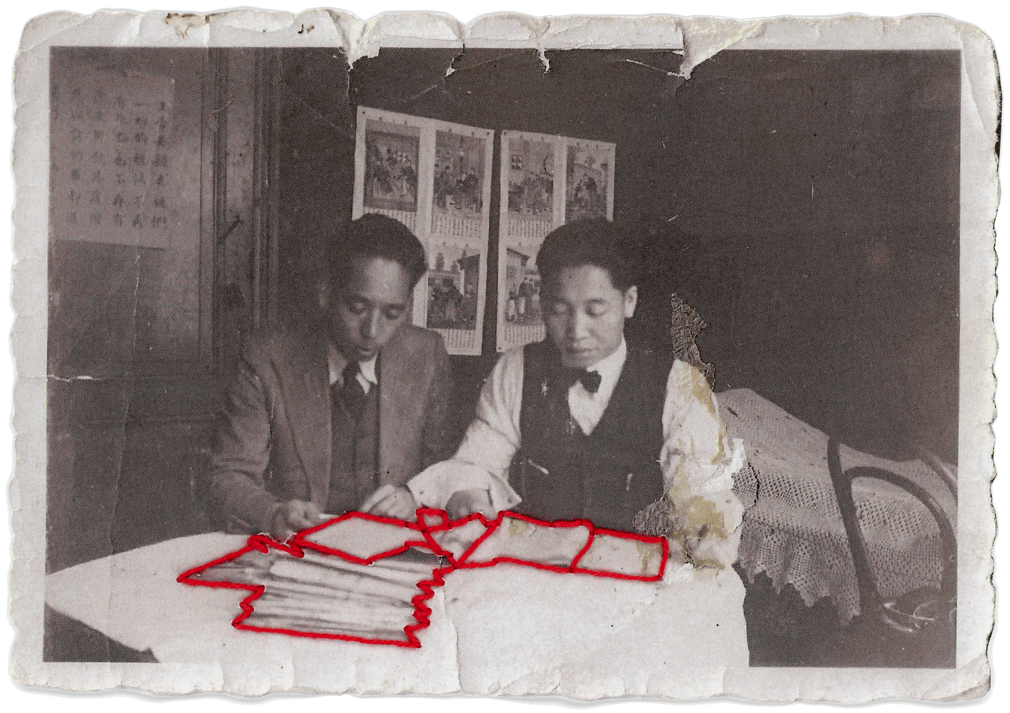 Black and white photograph of Laura Chen's grandfather in an office, with papers in front of him, which are sewn with red thread